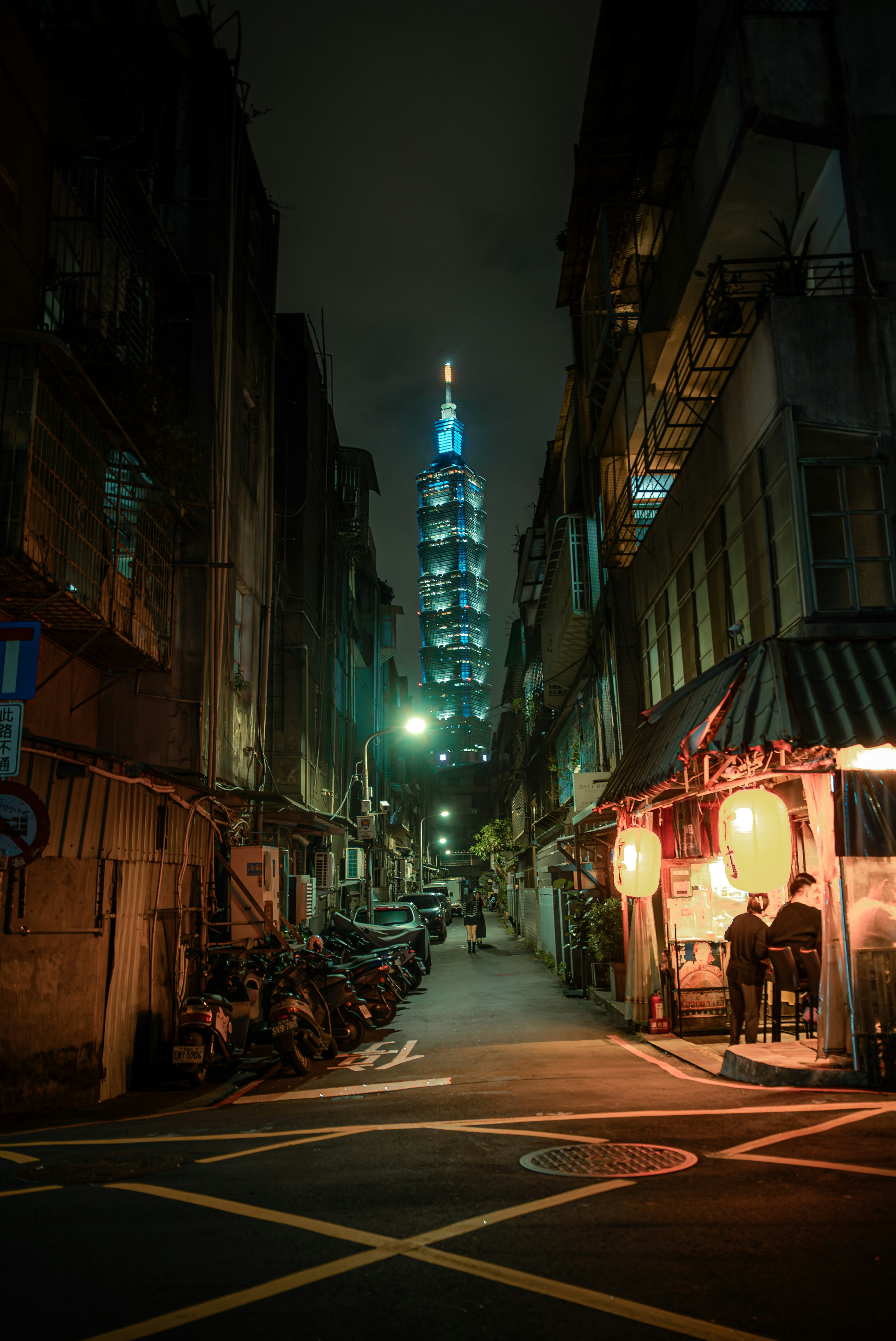 Blick auf eine enge Gasse mit beleuchtetem Taipei 101 in der Nacht