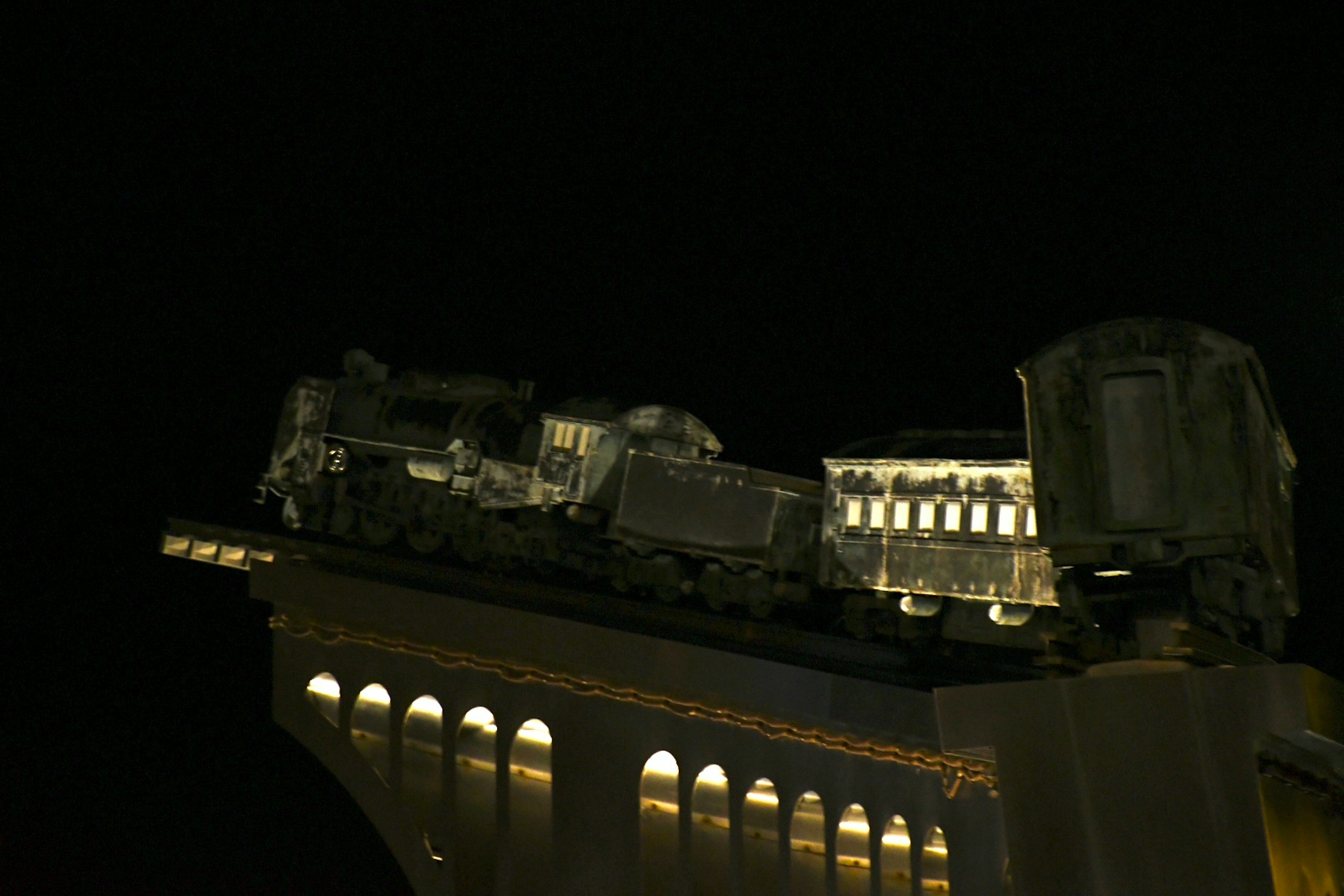 Sculpture of an old steam train and passenger car against the night sky