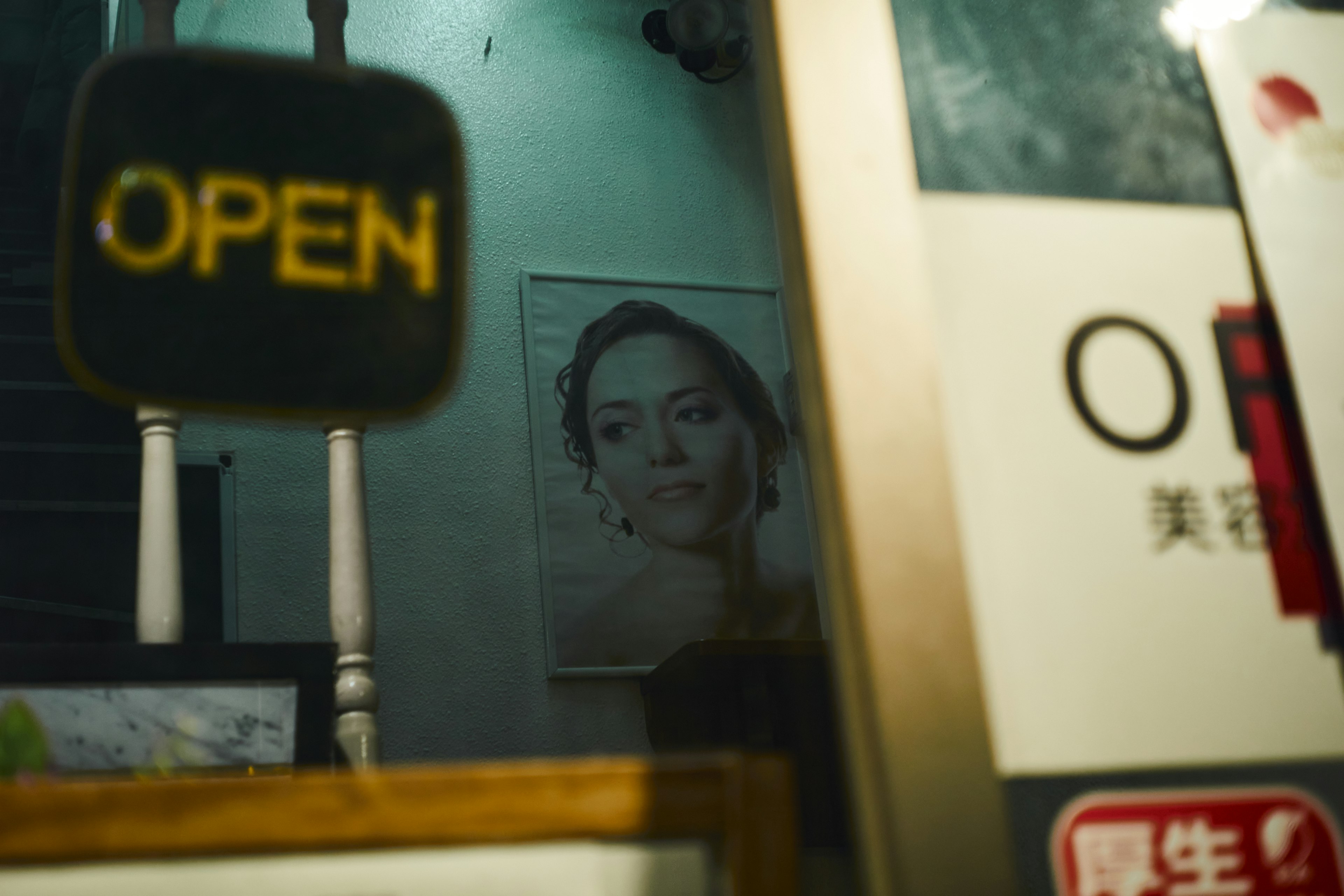 Offenes Schild sichtbar durch das Fenster mit einem Porträt einer Frau