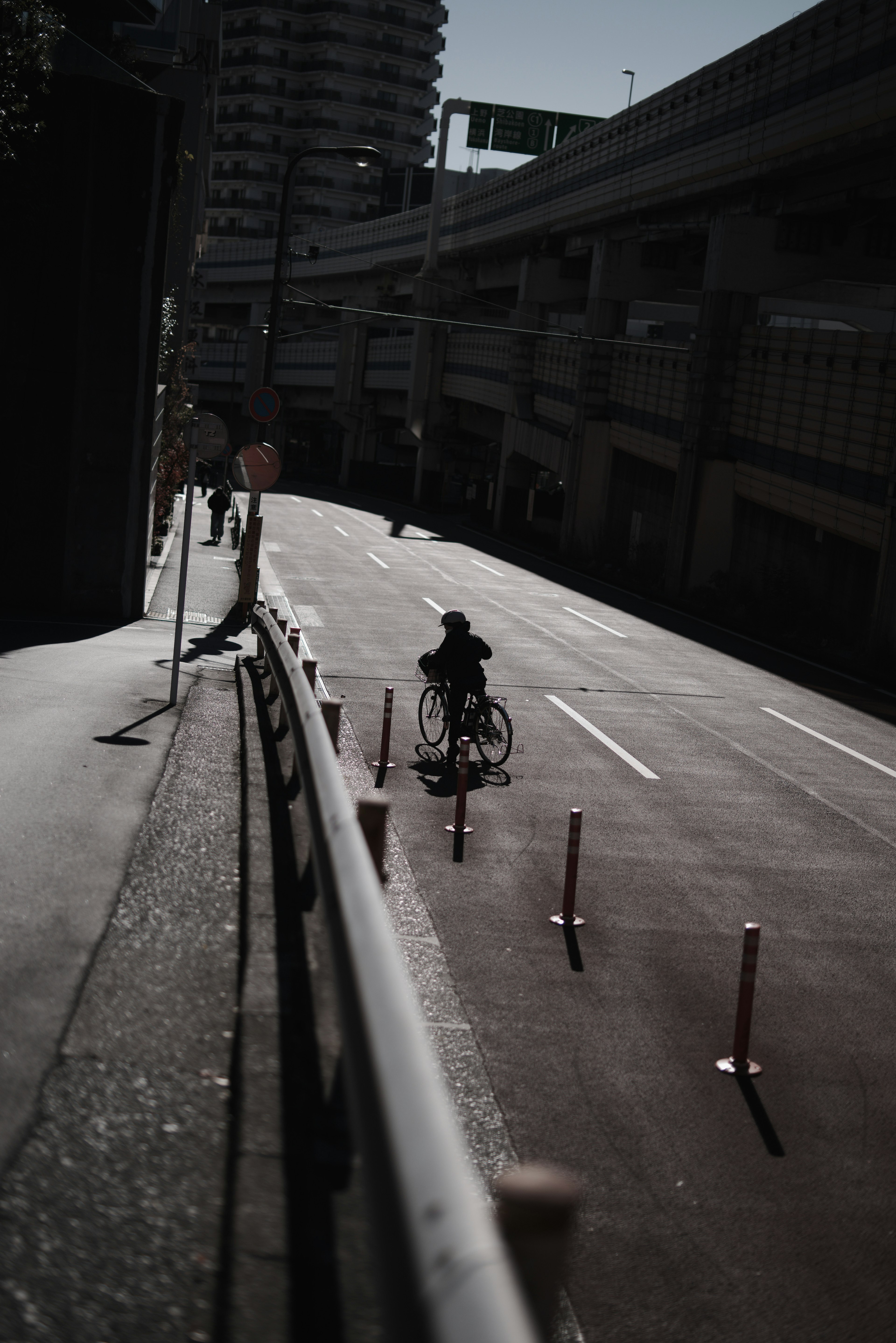 A person riding a bicycle on a dimly lit urban road