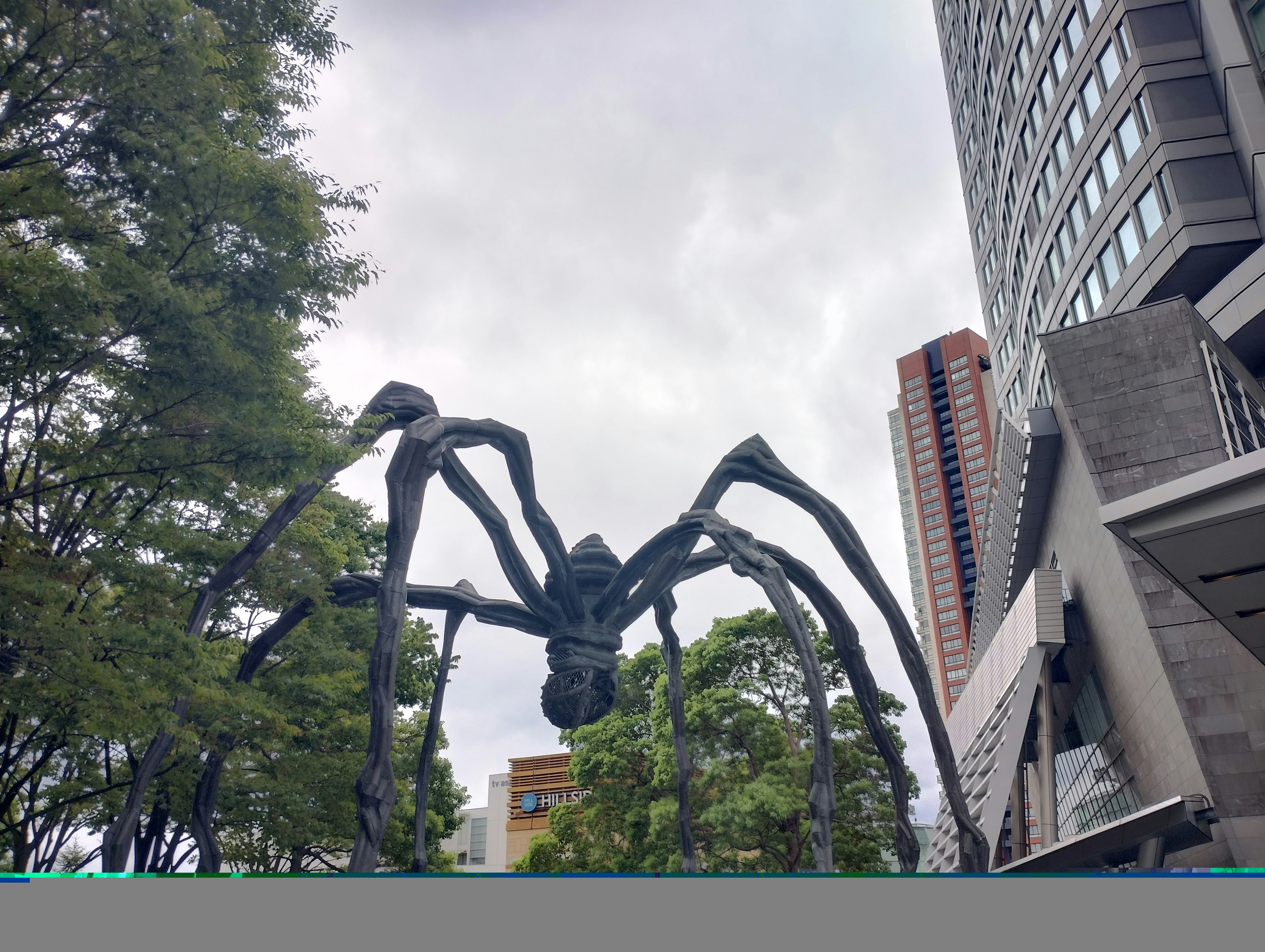 Una grande scultura di ragno si erge in un contesto urbano