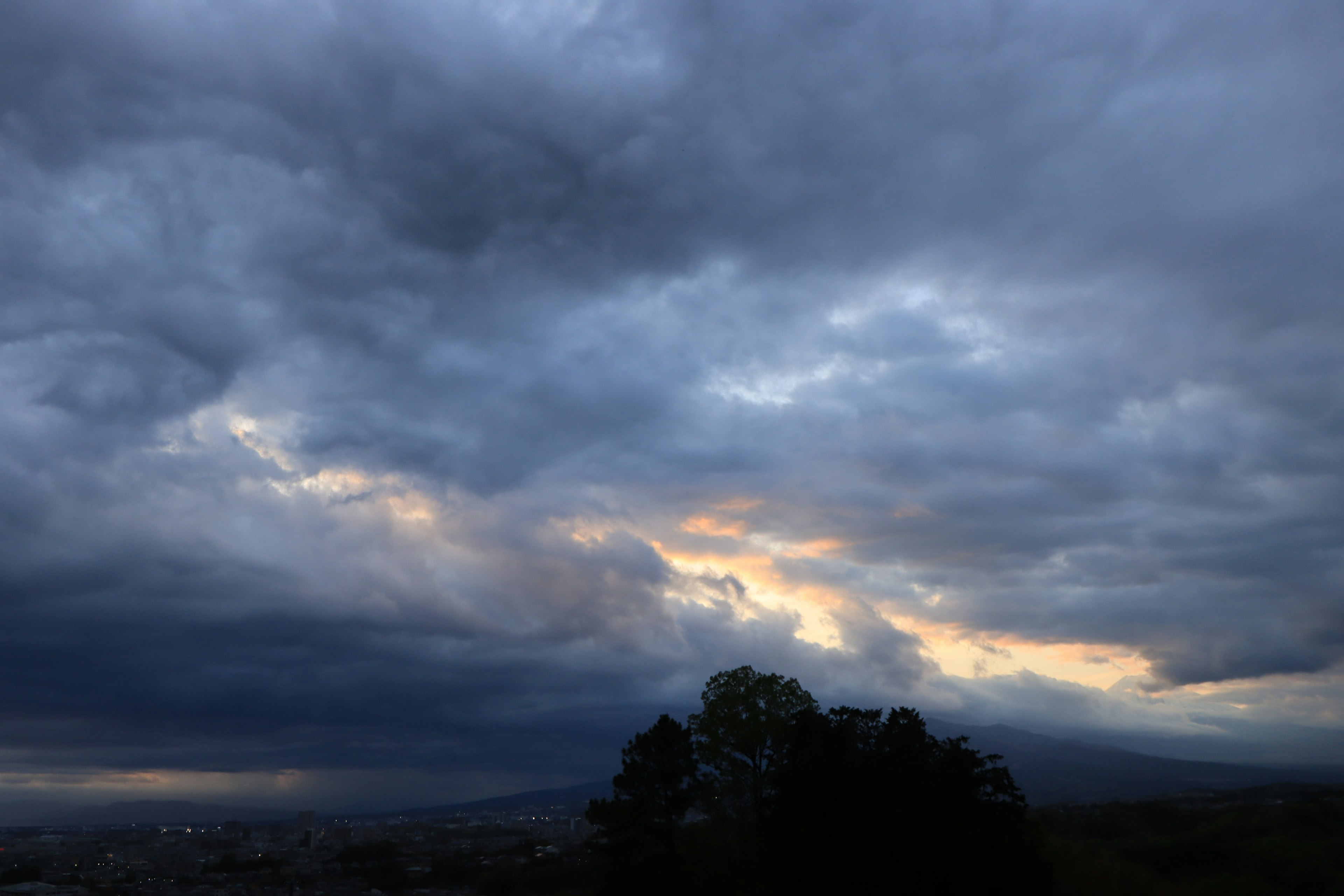 Ein dramatischer Himmel mit dunklen Wolken und orangefarbenen Lichtstrahlen