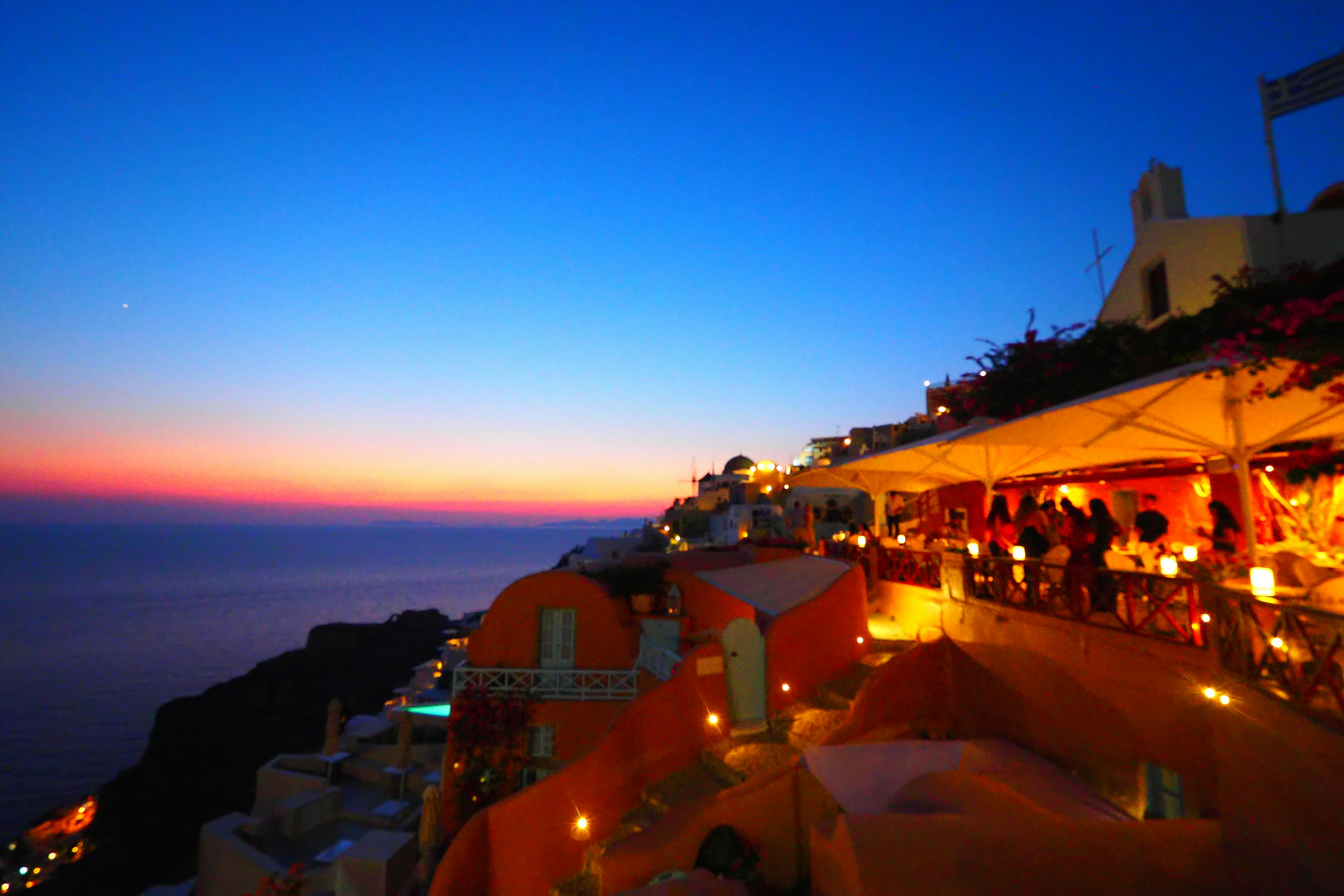 Tramonto a Santorini con terrazza illuminata e vista sull'oceano