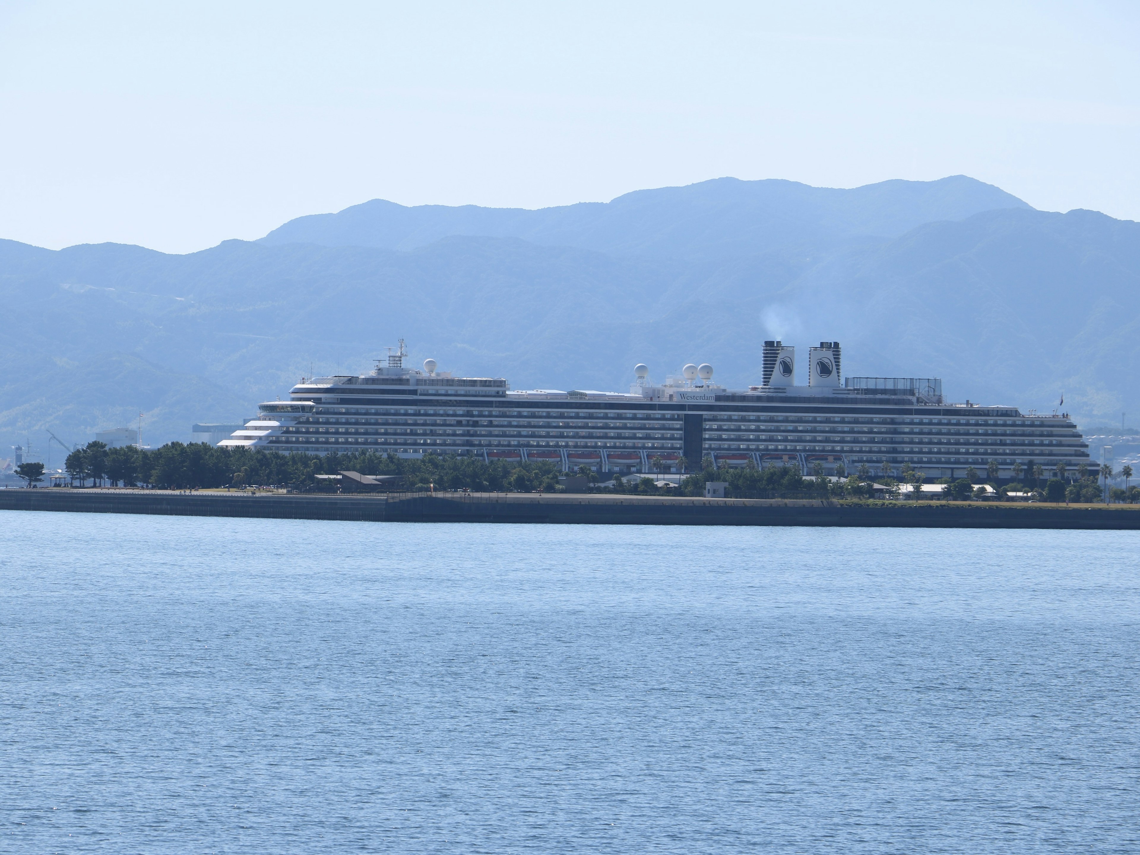 Large cruise ship near the shore with mountains in the background