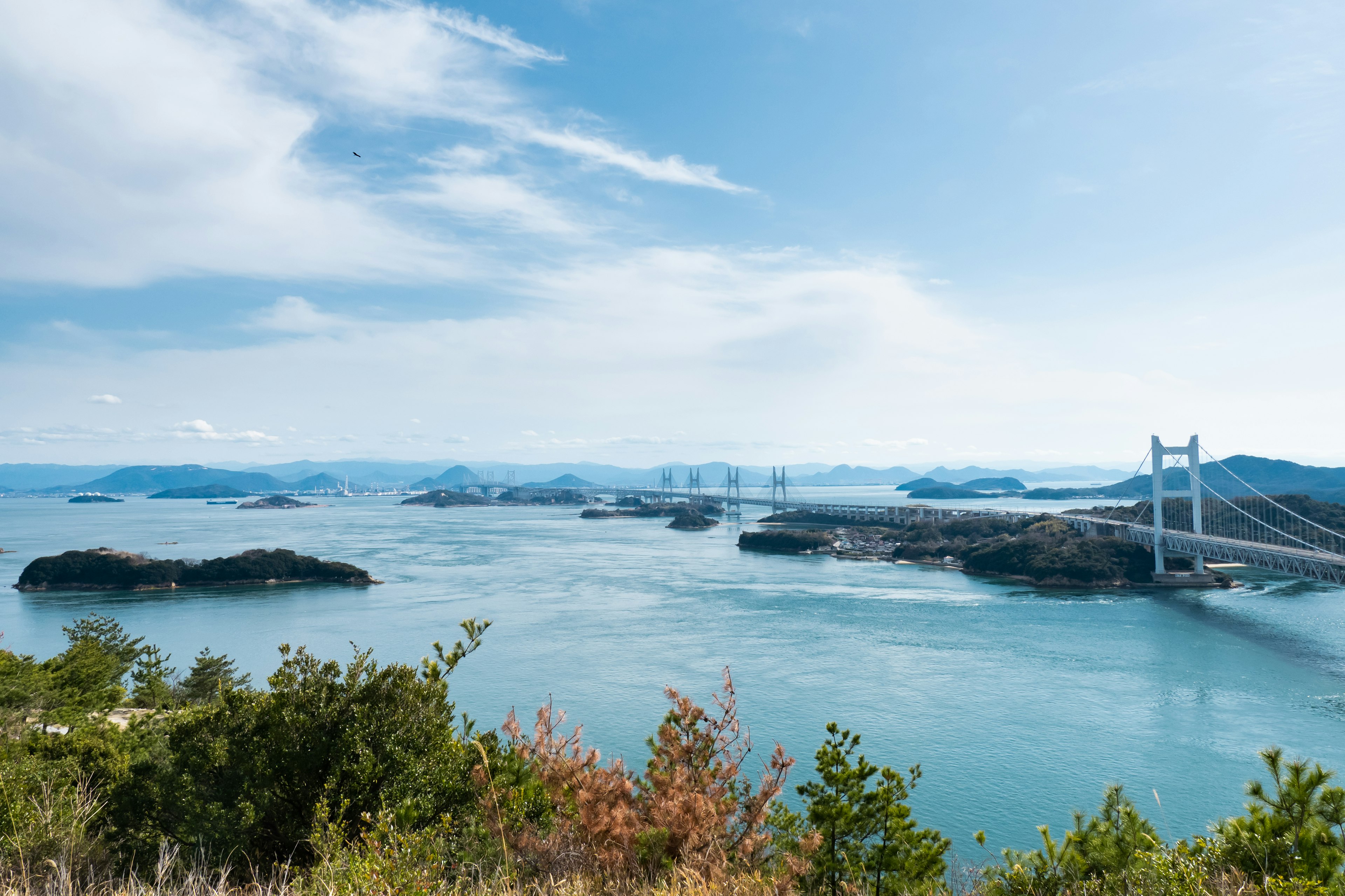 Scenic view of a blue sea with a bridge in the distance