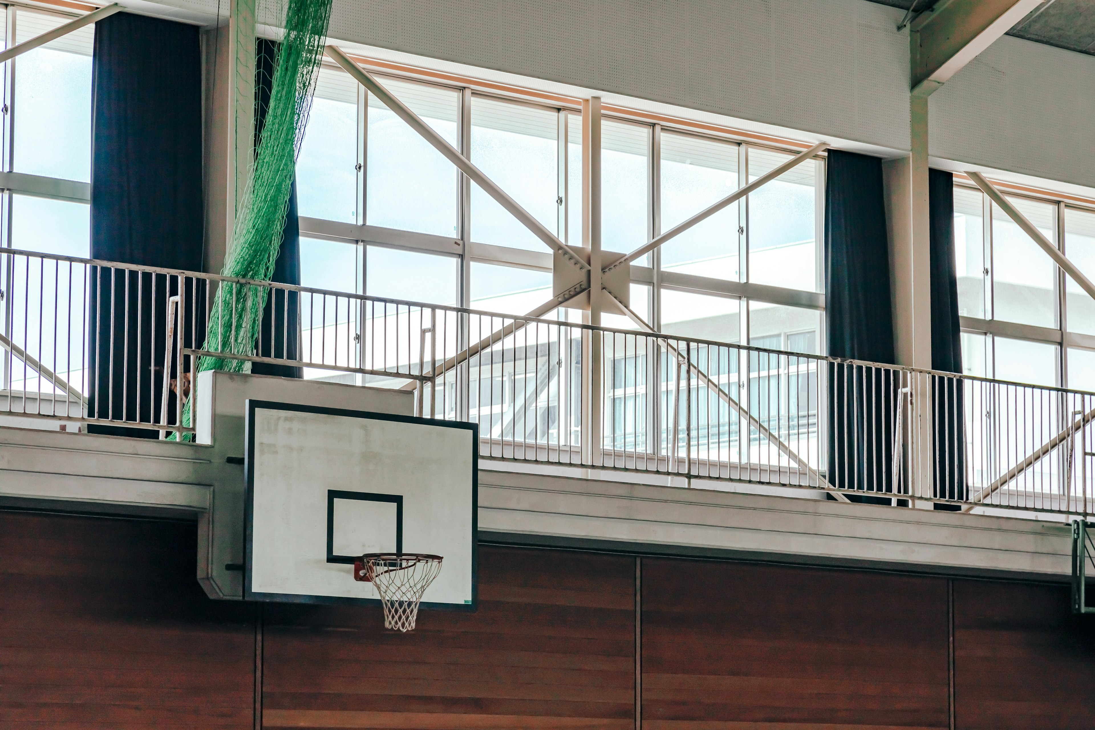 Scena luminosa di una palestra con un canestro da basket e grandi finestre