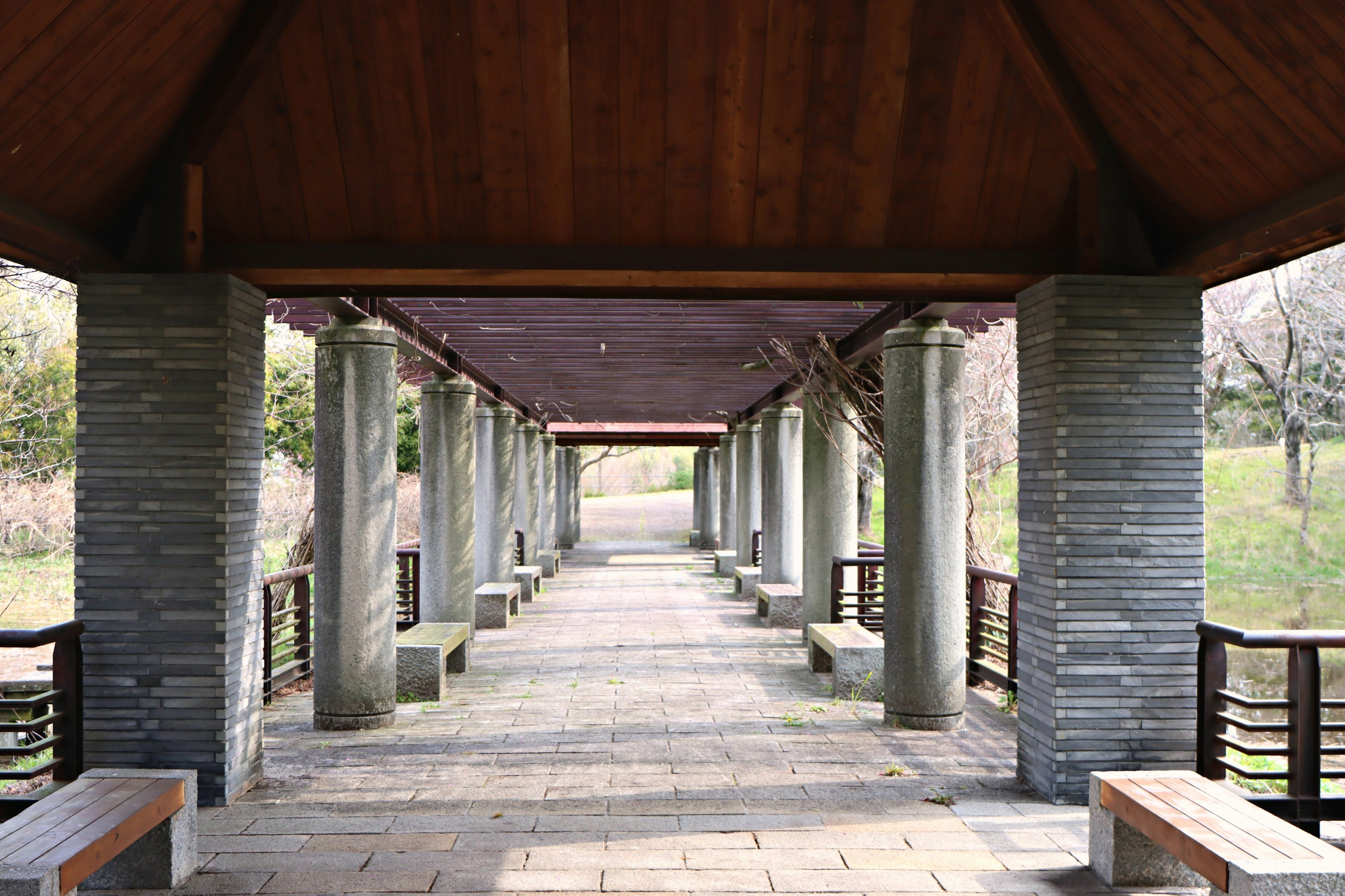 View of a covered walkway with wooden roof and stone pavement