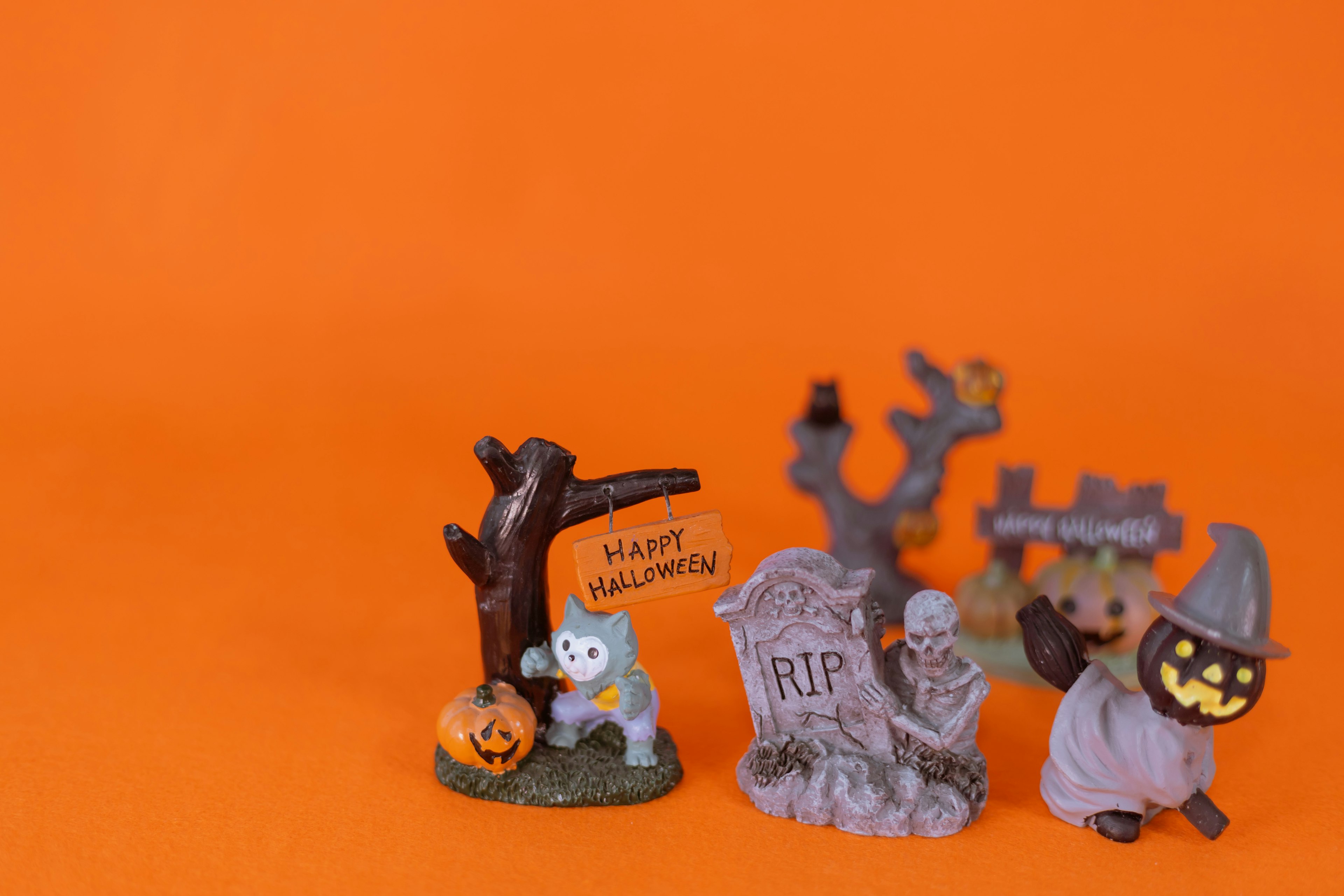 Halloween decorations featuring a pumpkin, gravestone, and spooky characters on an orange background