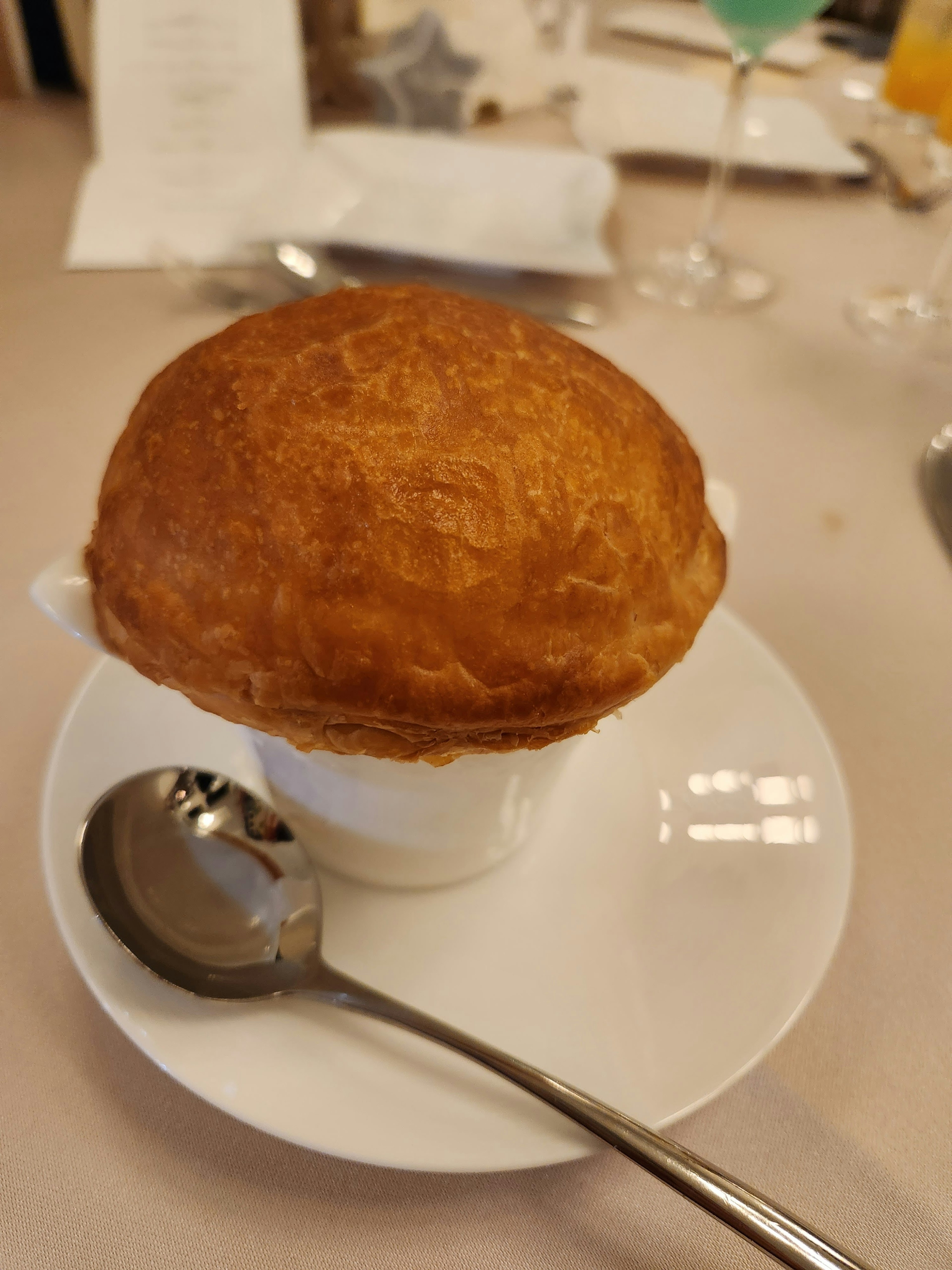 Soufflé dorado en una taza blanca con una cuchara de plata