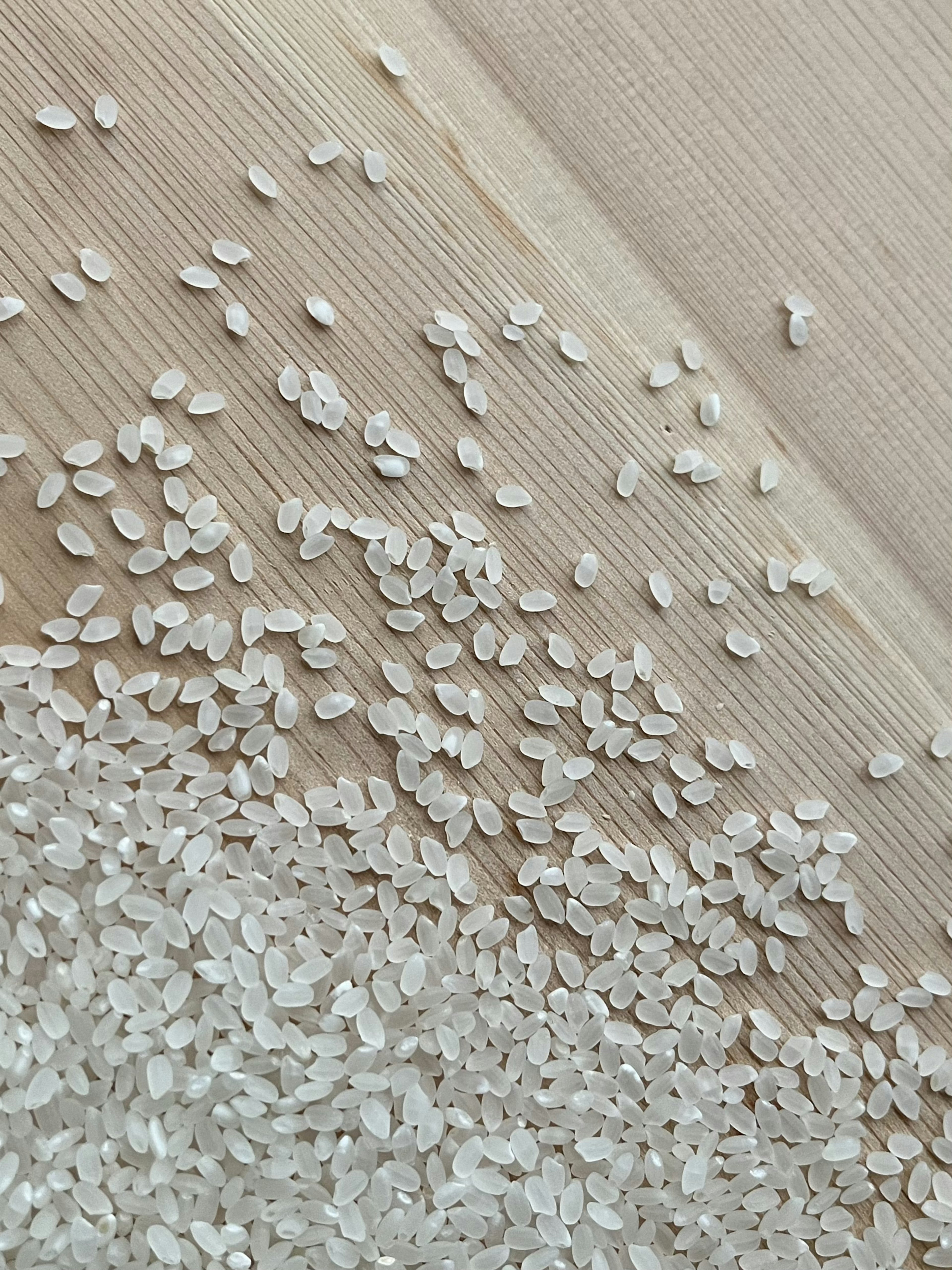 Scattered white rice grains on a wooden surface