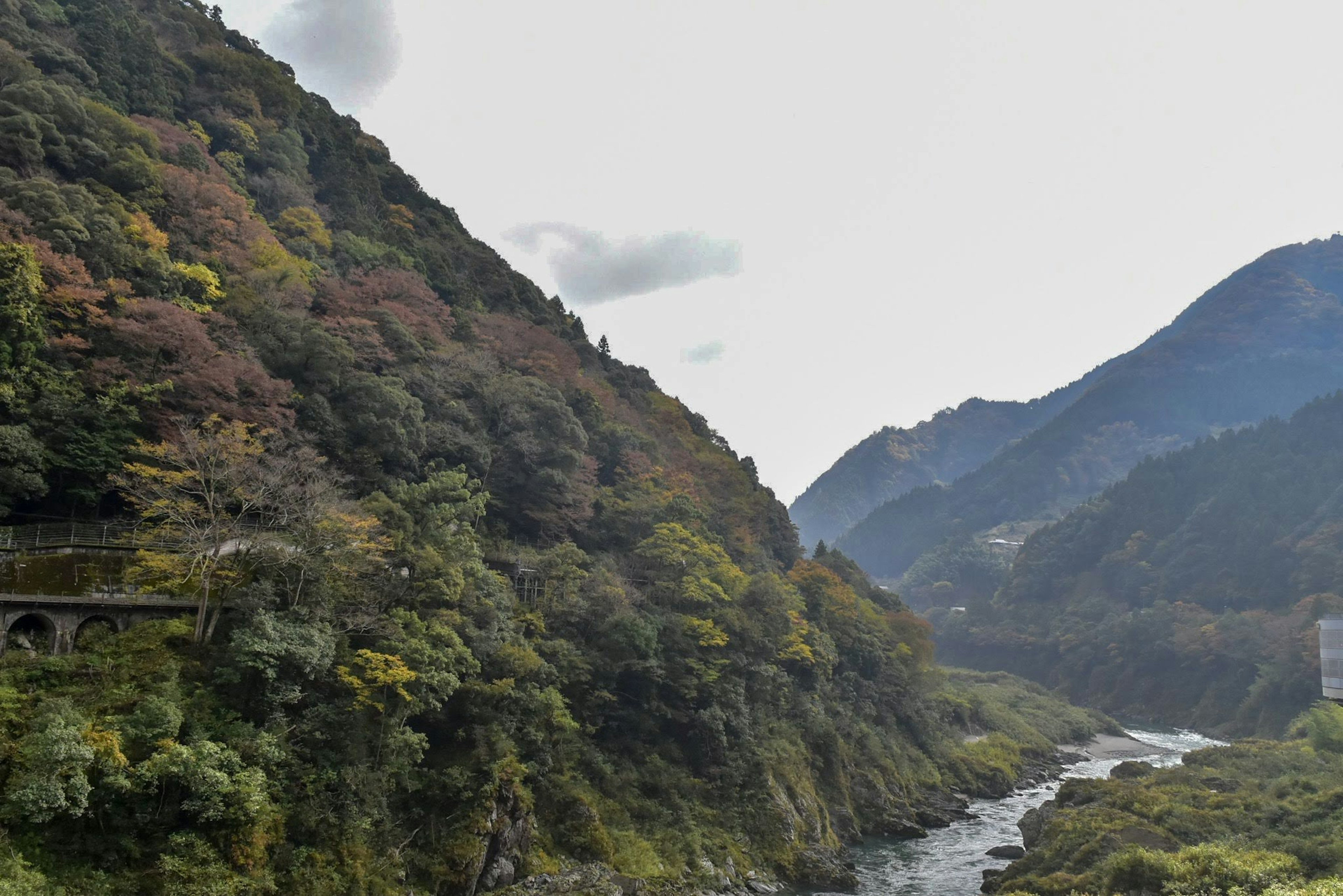 Malersiche Aussicht umgeben von Bergen und Fluss mit üppigem Grün und Herbstfarben