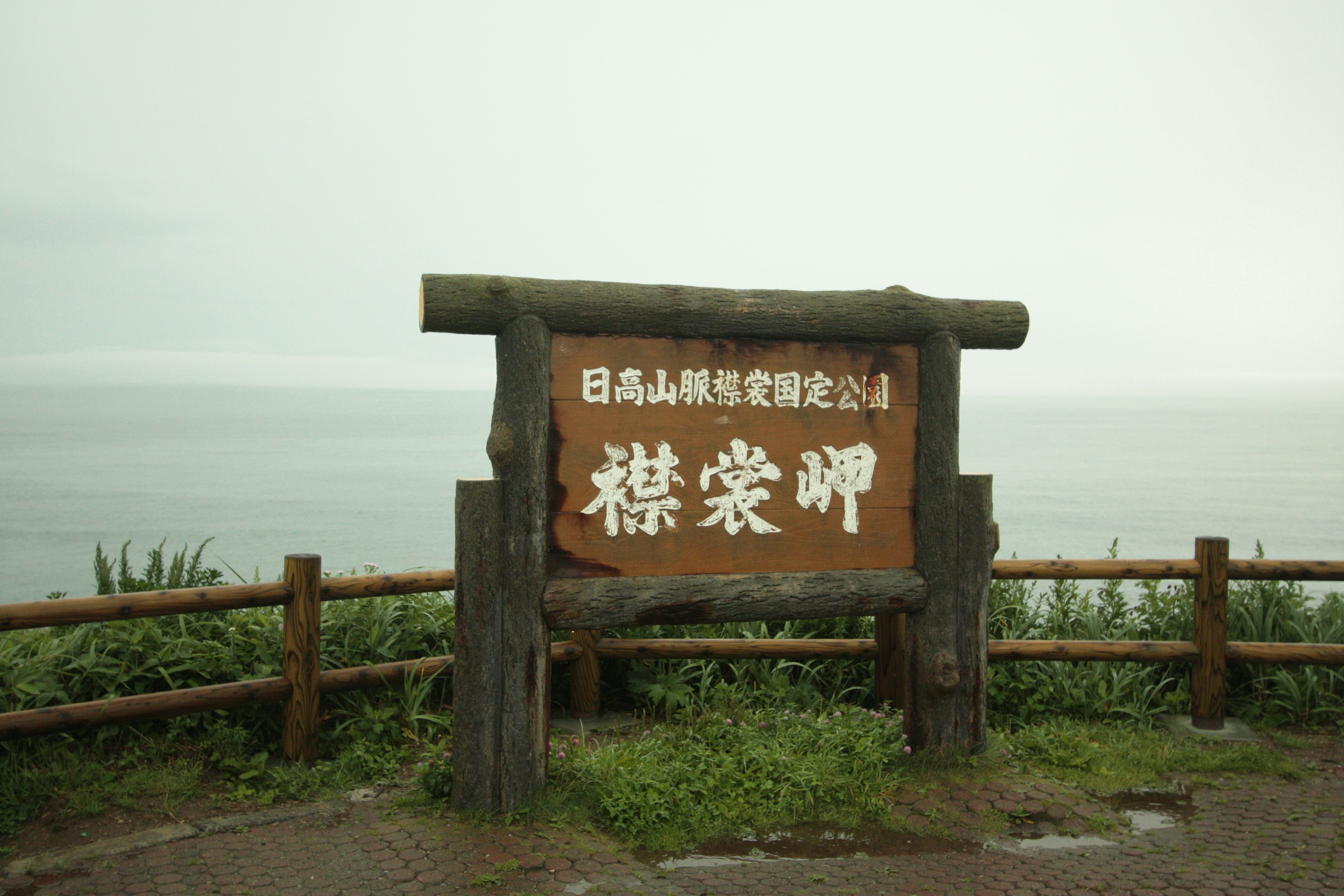 木製標誌，上面寫有日高山脈國家公園的名字，背景是海景