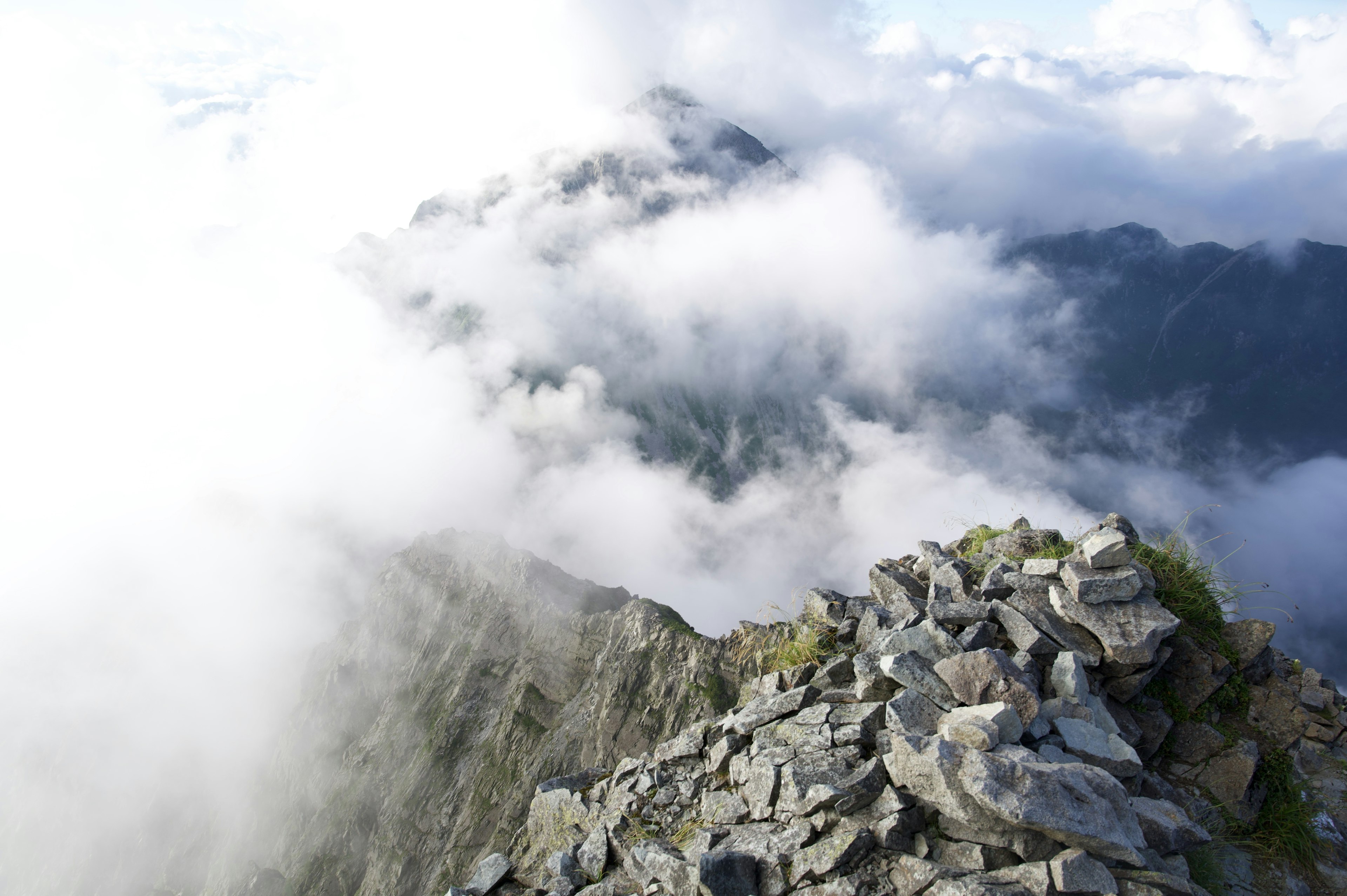 Vista desde la cima de la montaña con terreno rocoso y nubes