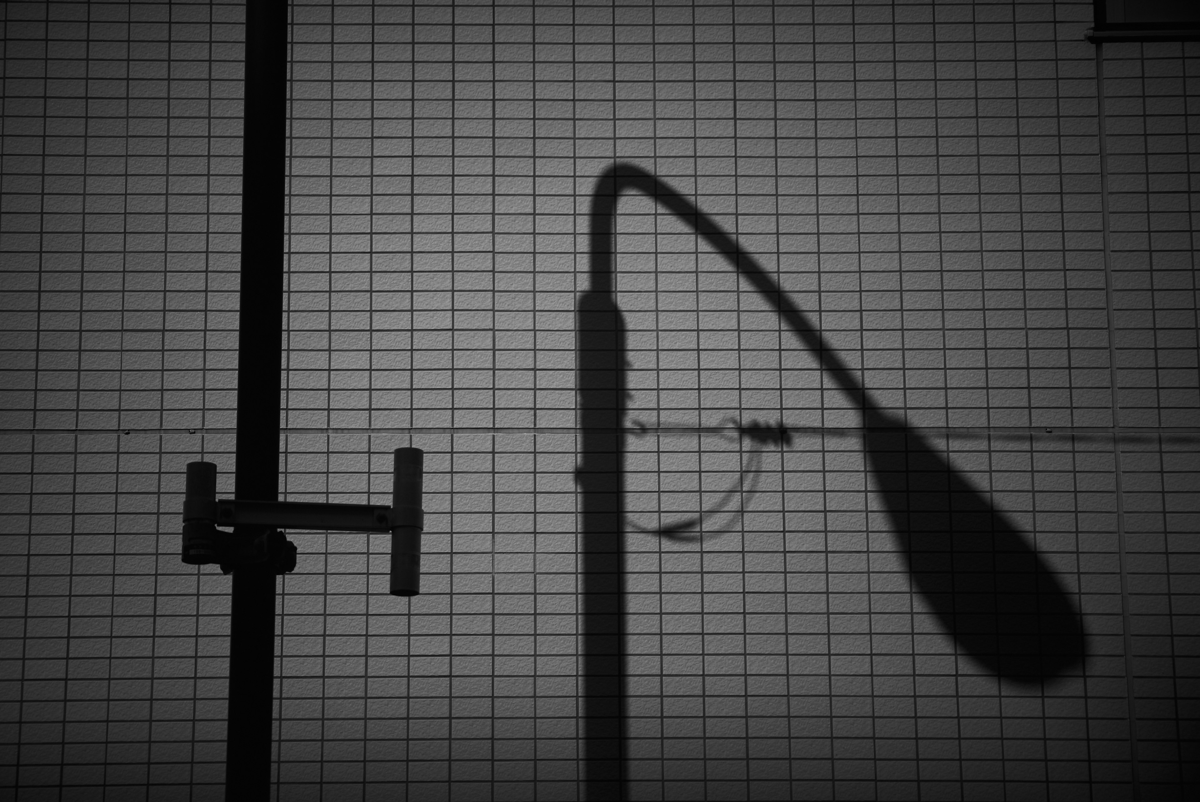 Shadow of a streetlight and metal pipe on a black and white grid background