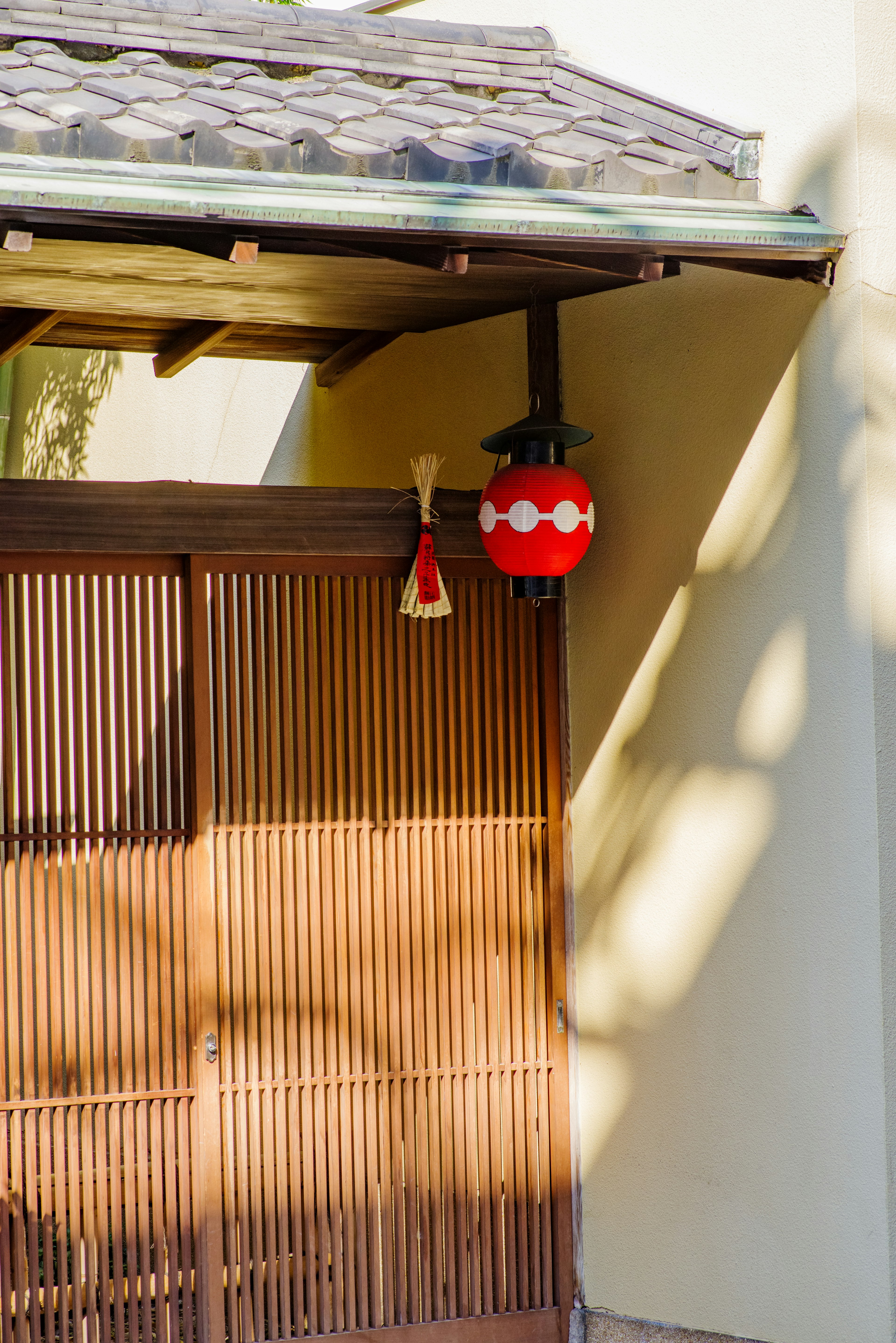 Ingresso di una casa giapponese tradizionale con porta in legno e lanterna rossa