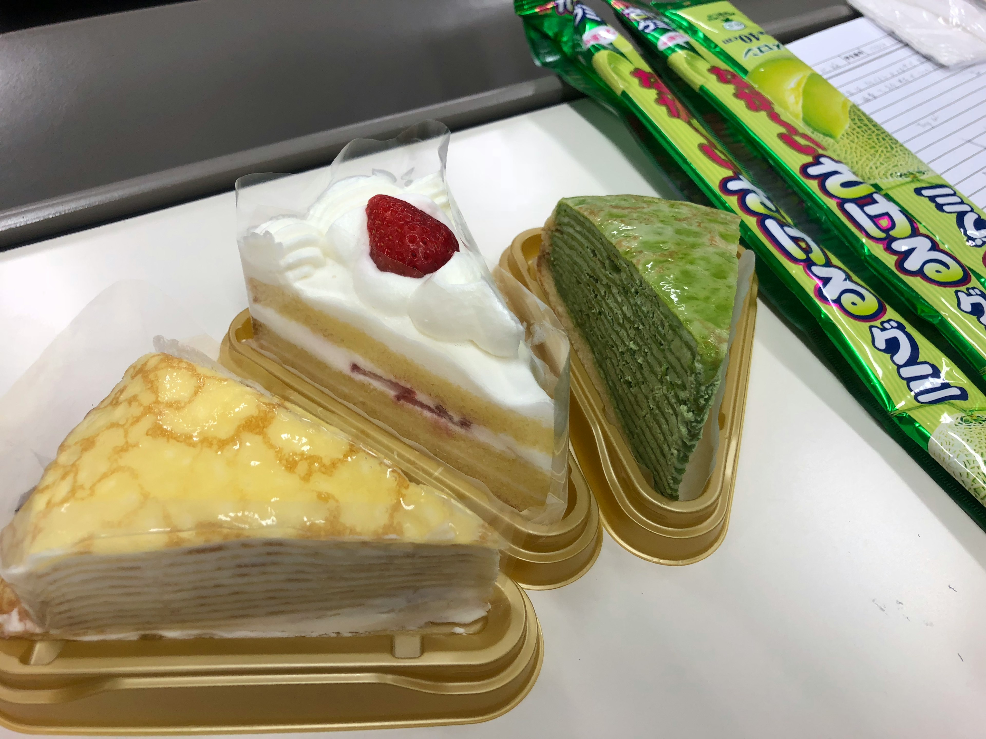 三角形のケーキが二つとホイップクリームとイチゴが乗ったケーキが一つの画像