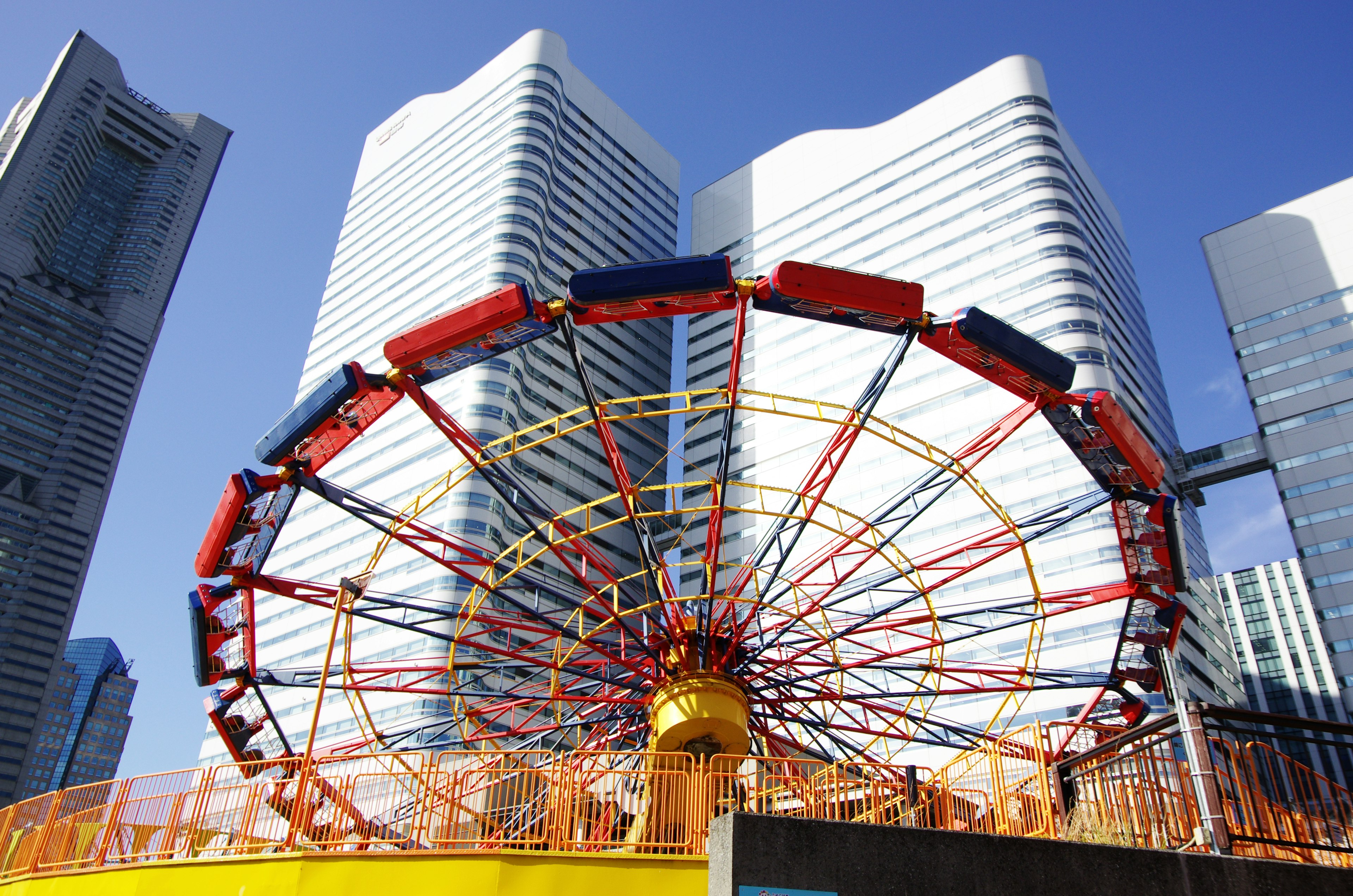 Colorful ferris wheel between modern skyscrapers