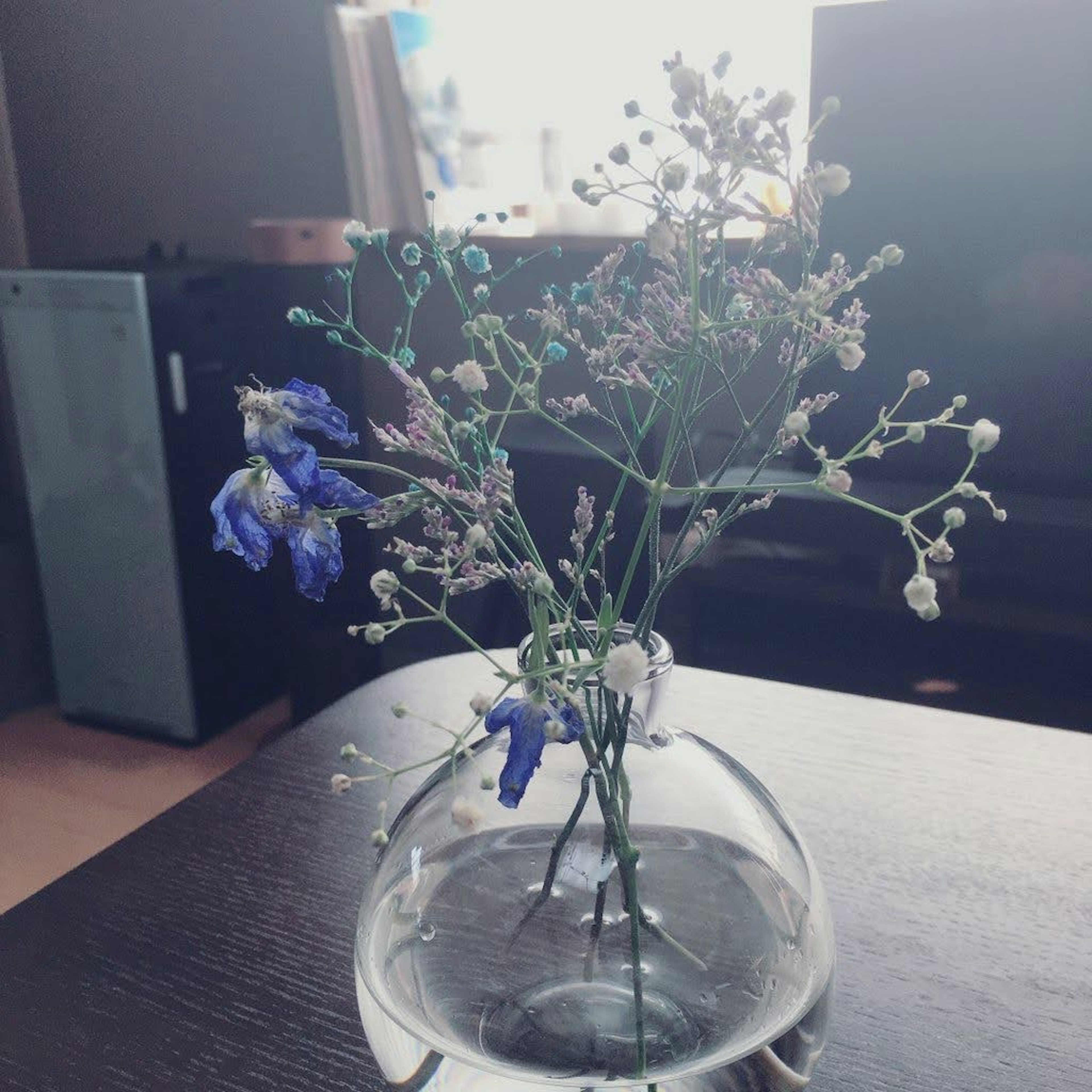 Arrangement de fleurs bleues et de petites fleurs blanches dans un vase transparent