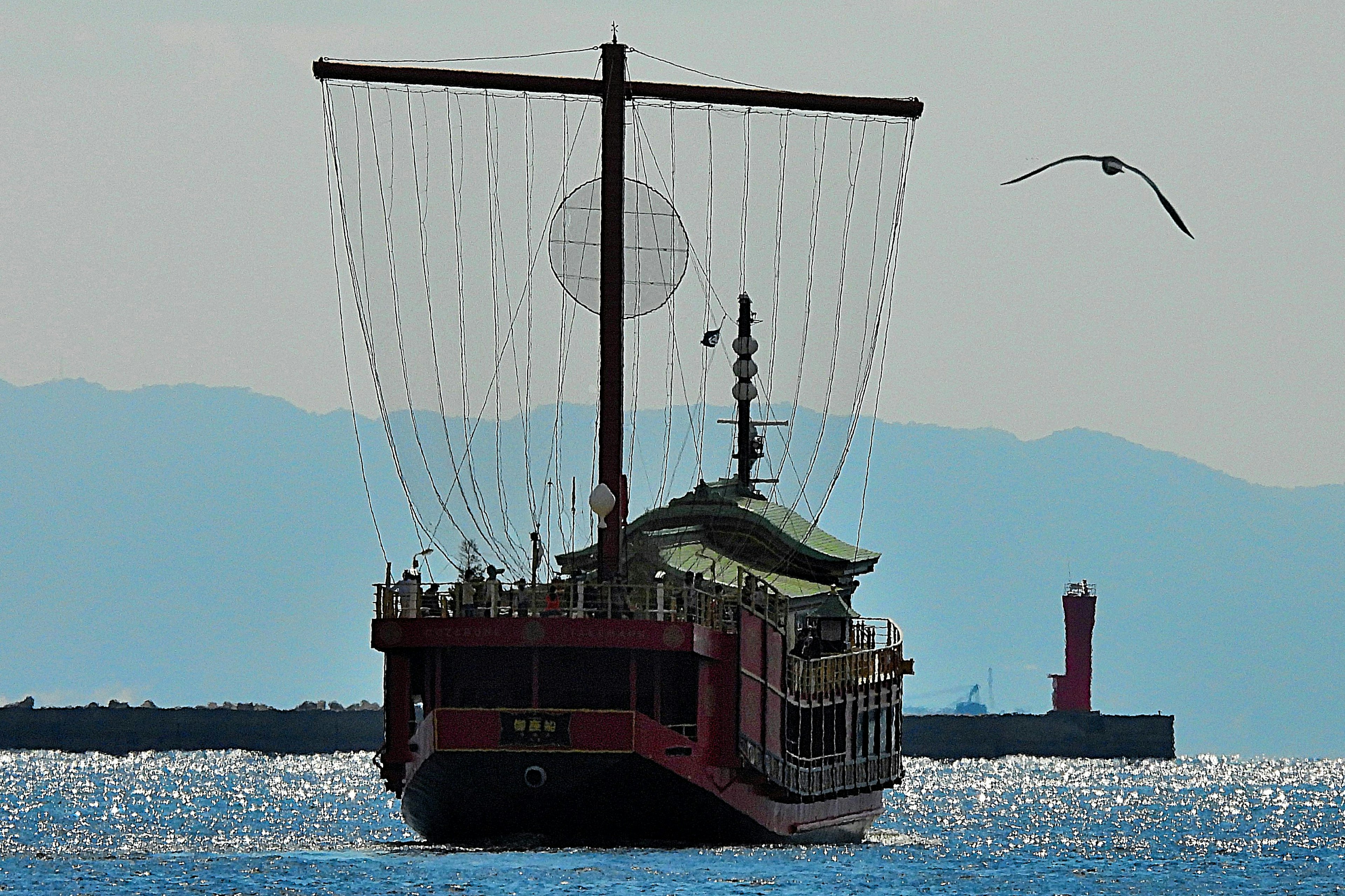 Traditional boat sailing on water with mountains in the background