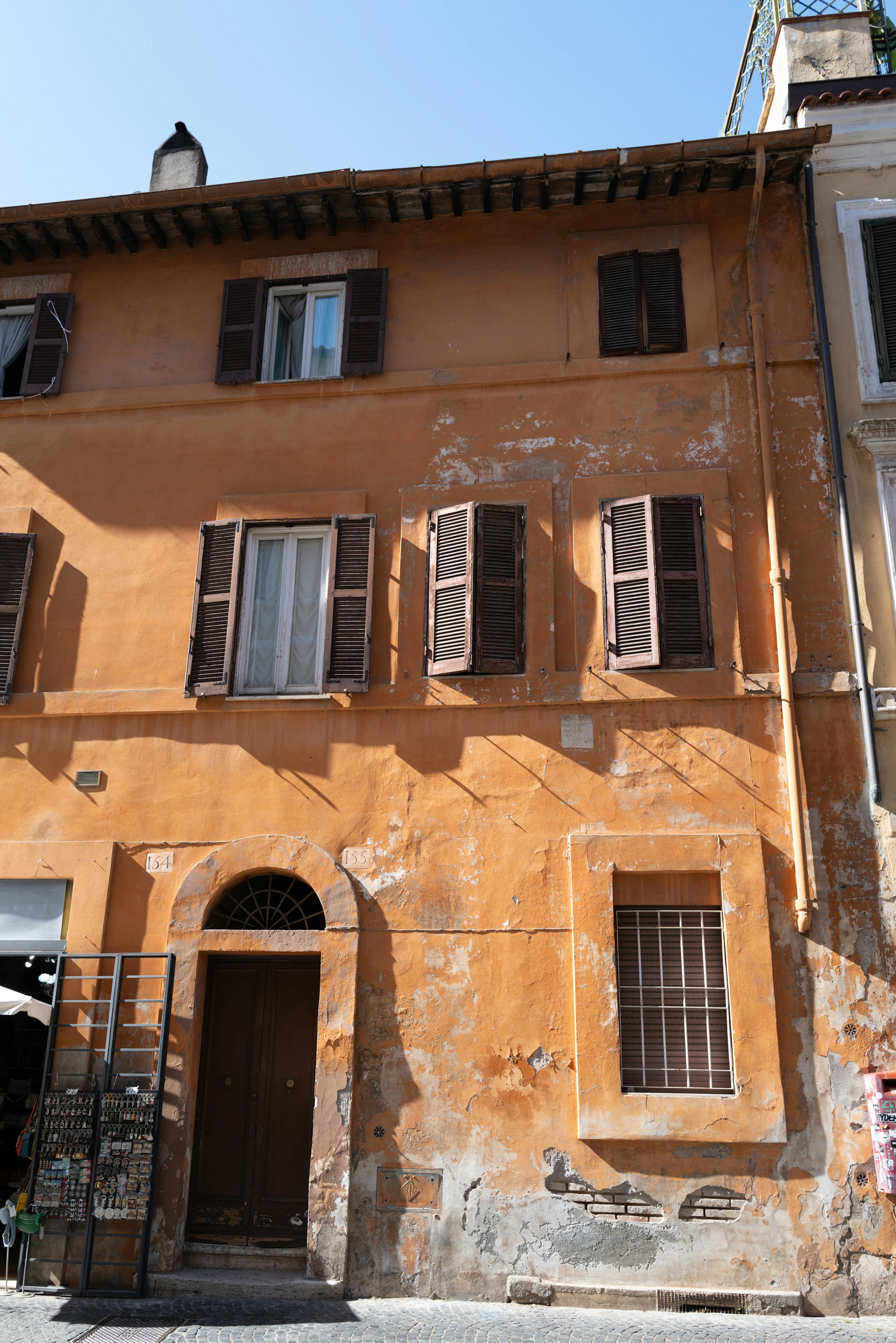 Facade of an old building with orange exterior walls Wooden shutters on the windows with weathered paint