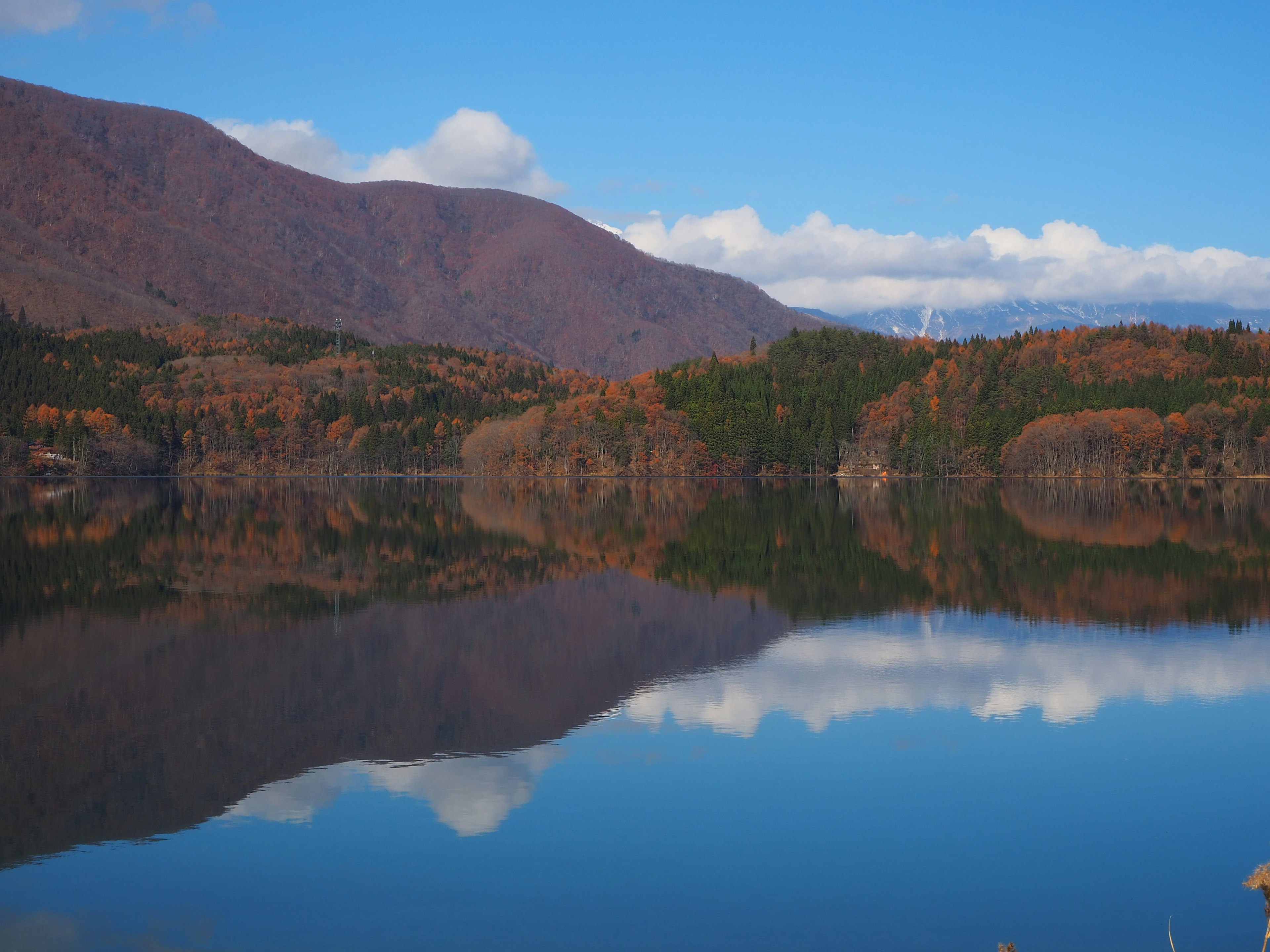 Paisaje sereno de un lago con montañas circundantes y follaje otoñal