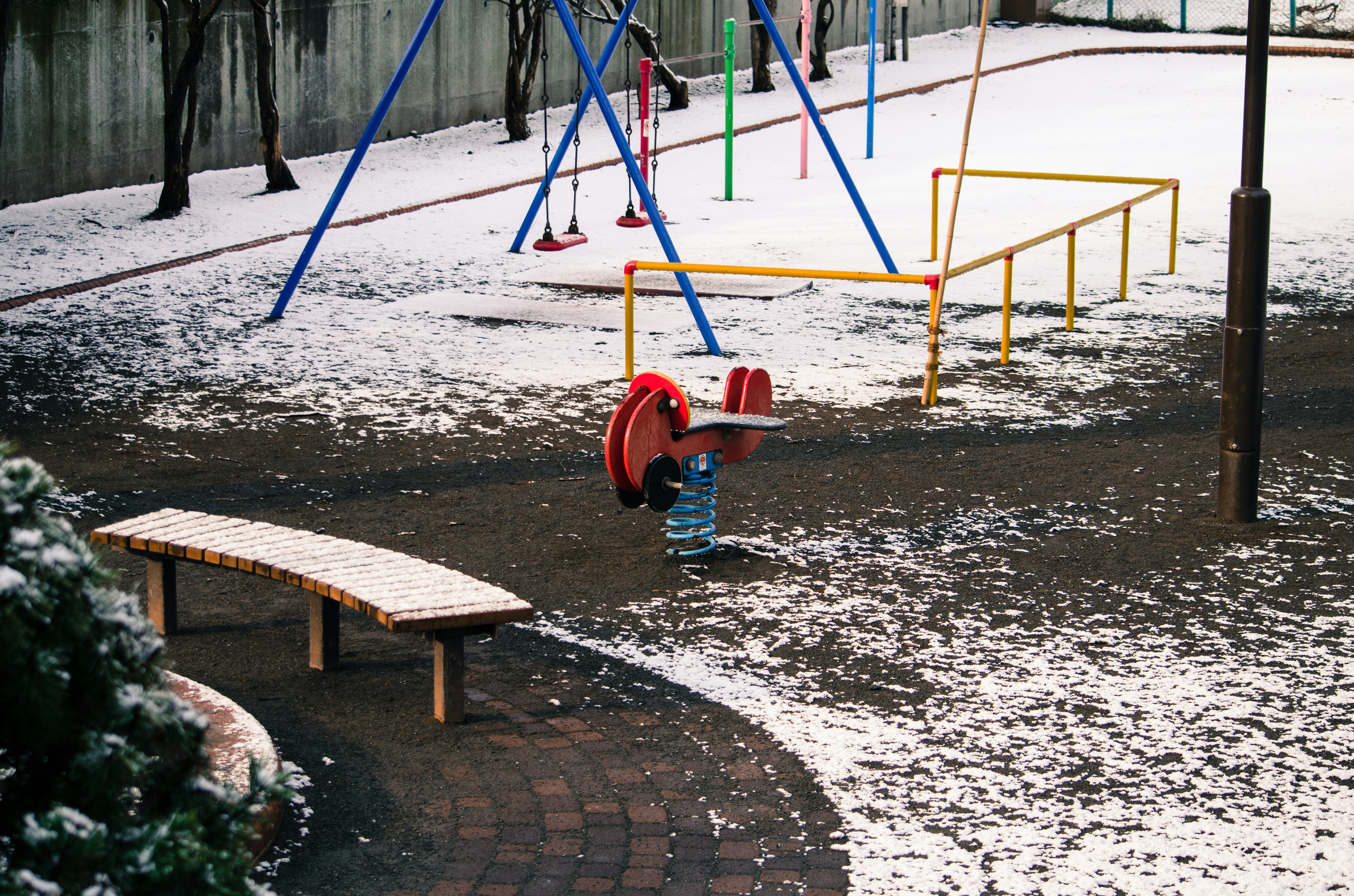 Parco giochi con altalene e panchina coperte di neve