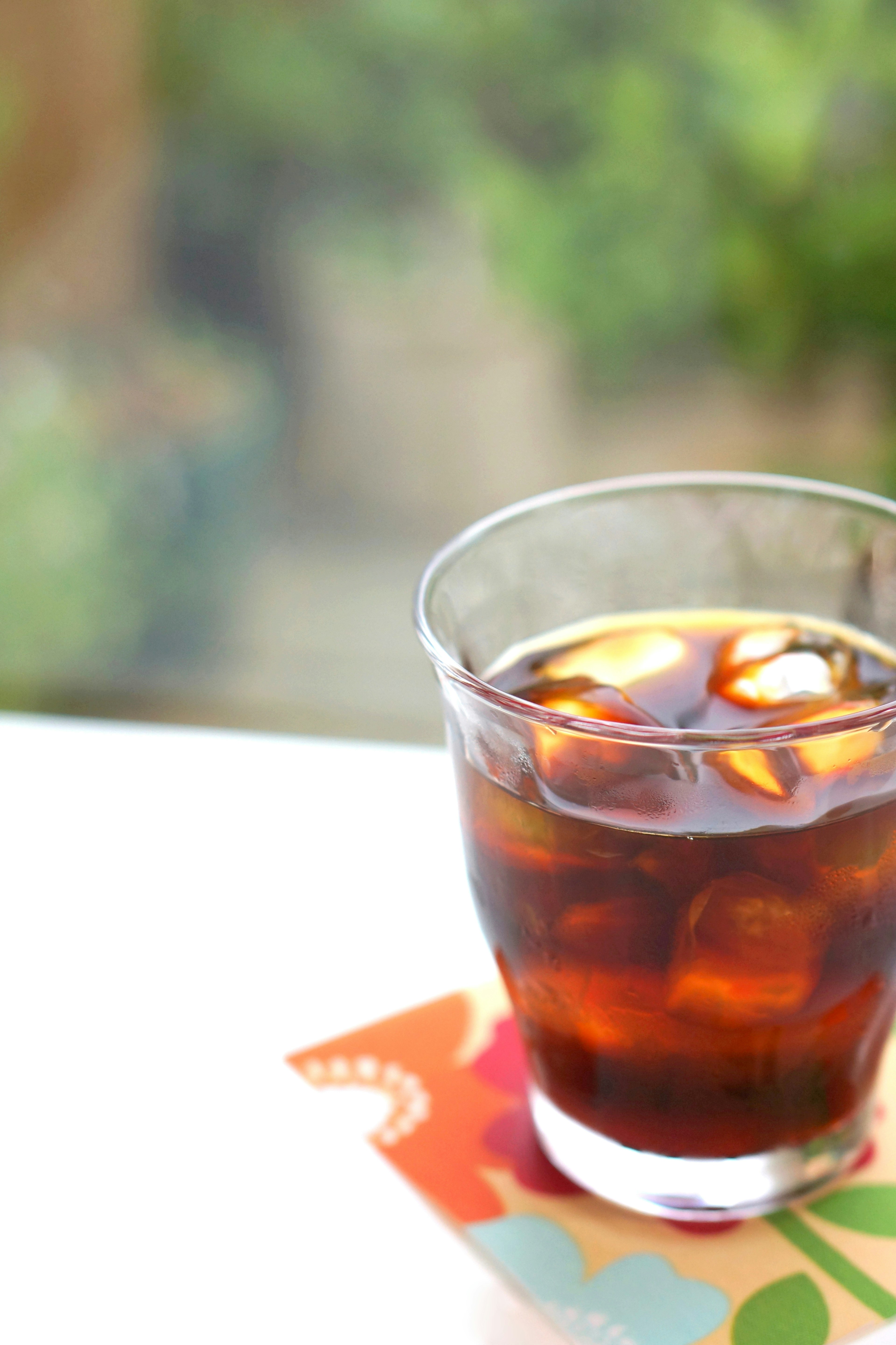 A glass of iced coffee with ice cubes on a colorful coaster