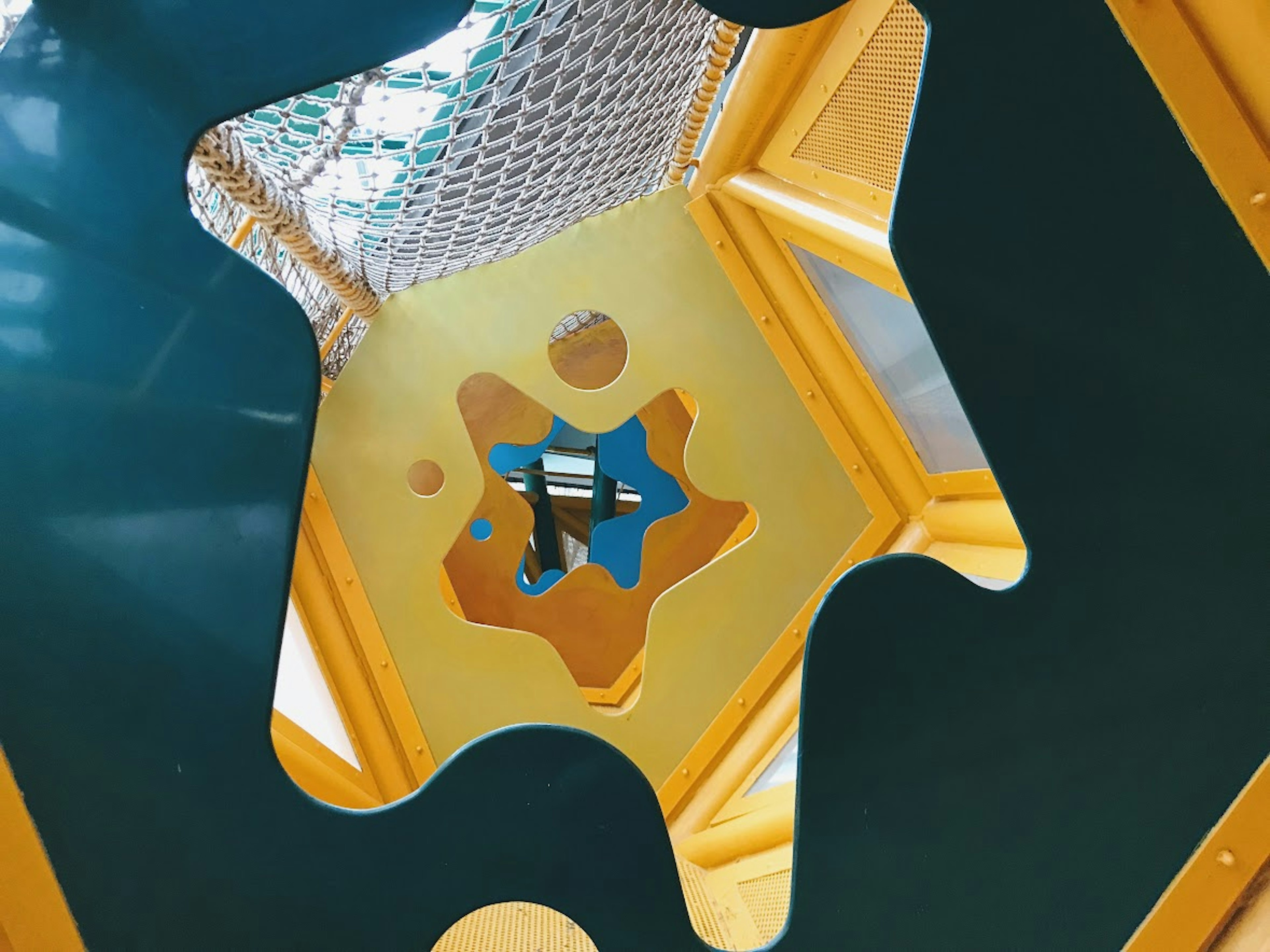 View from inside a playground structure showing yellow and green colors with a blue star decoration