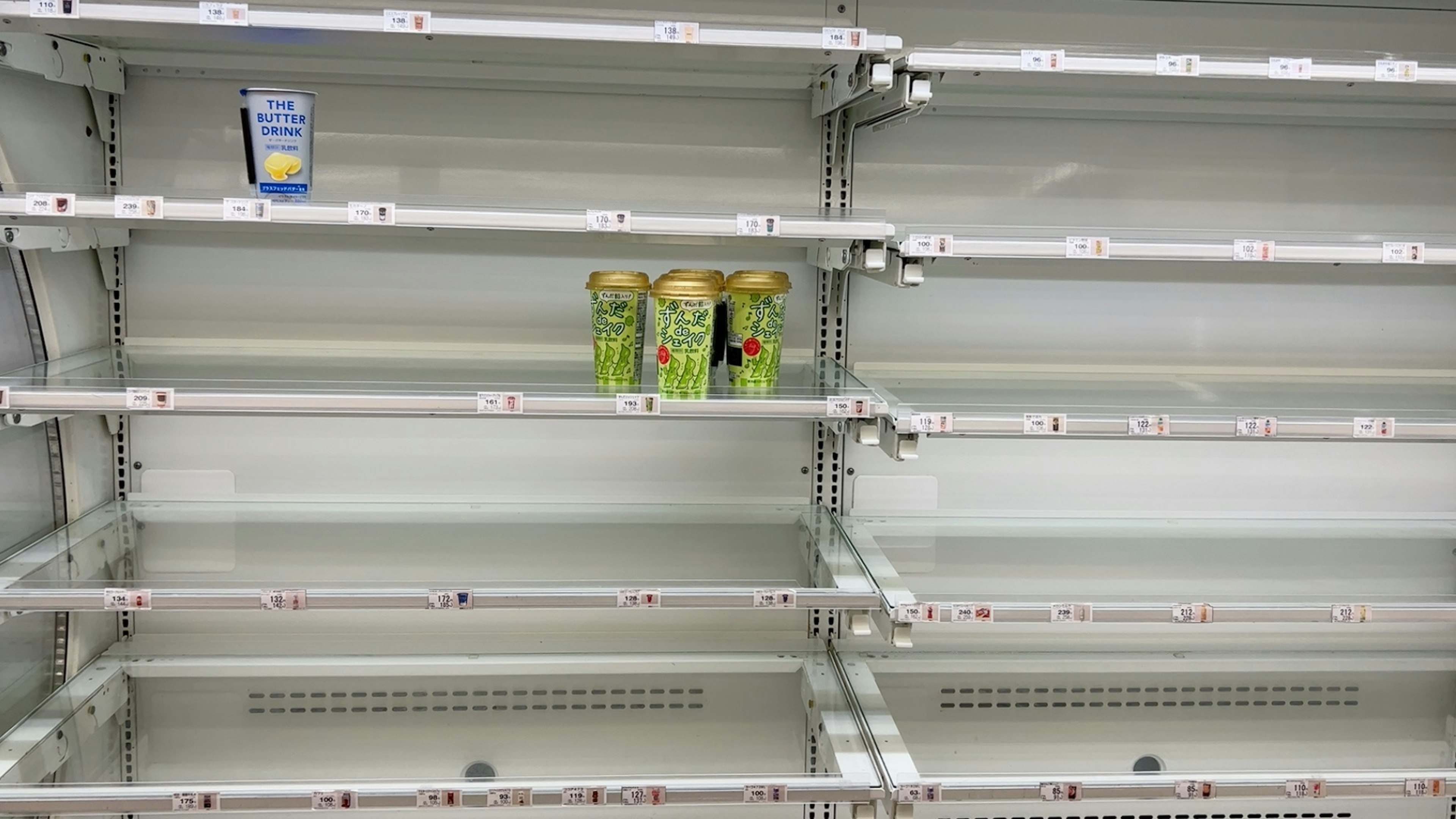 Refrigerator shelf with drinks and empty spaces