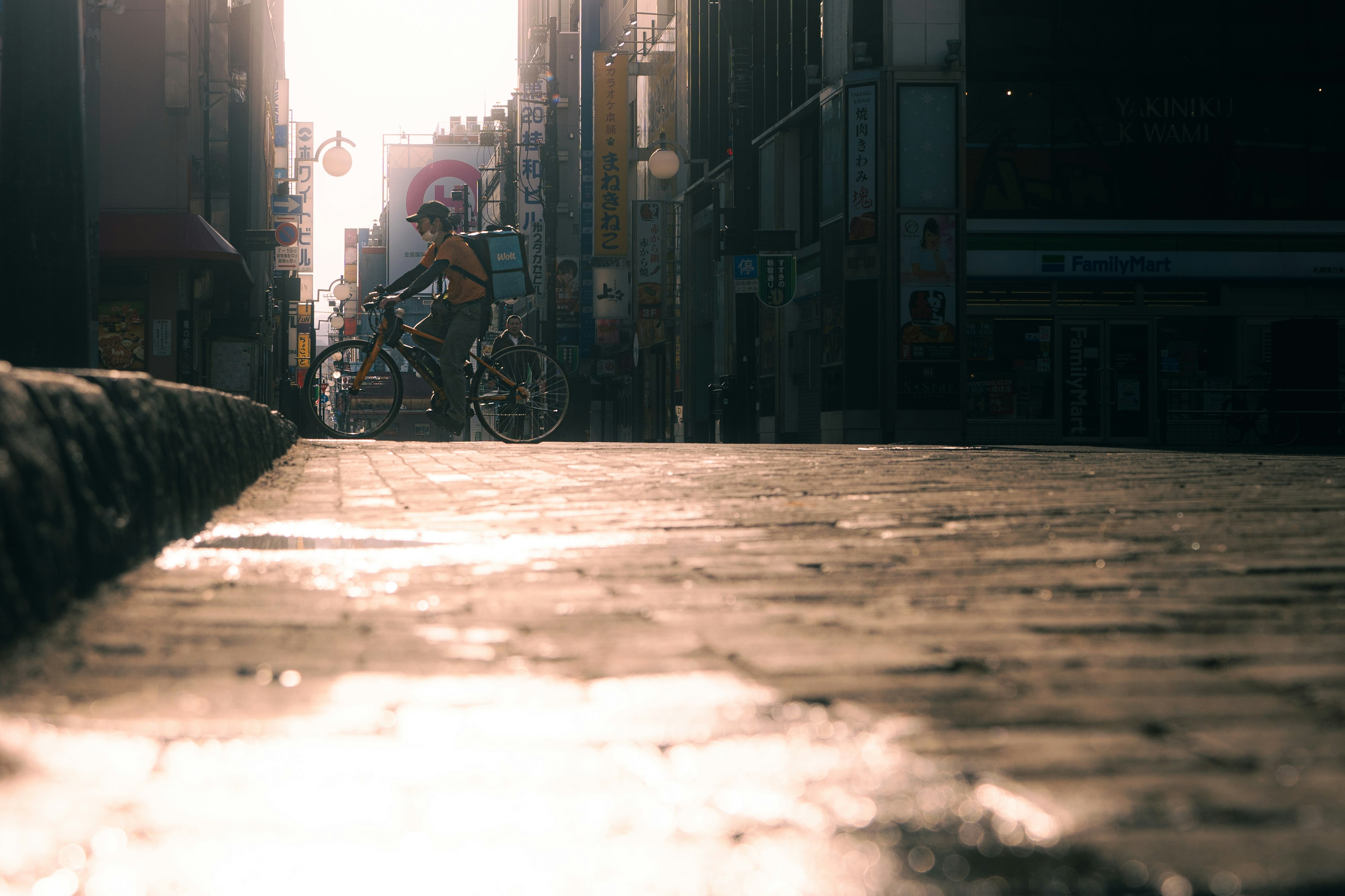 Bicycle riding down a sunlit street with reflections on the pavement