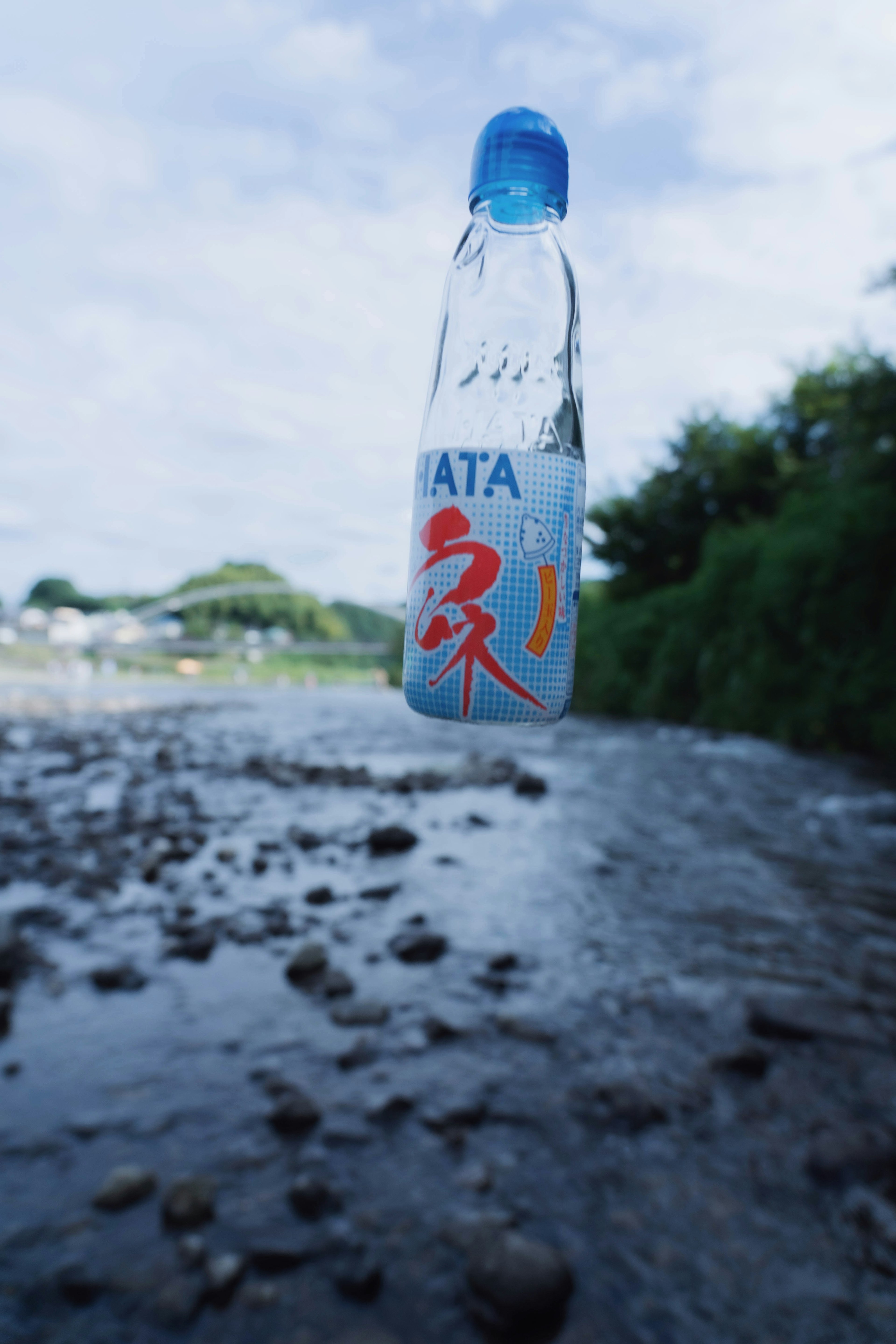 Botella de plástico transparente flotando sobre un río con tapa azul y letras rojas