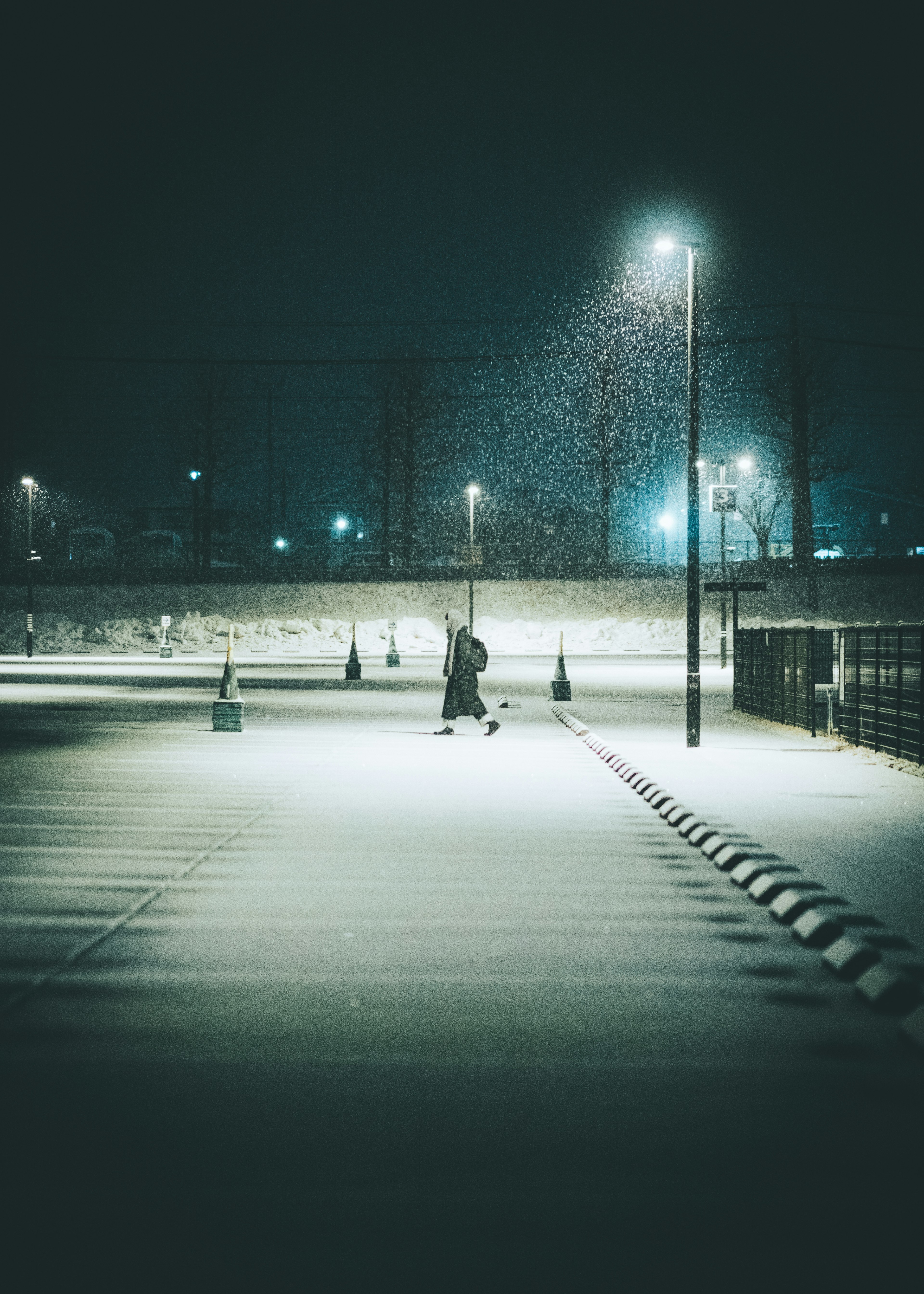 Une personne marchant dans la neige lors d'une nuit calme avec des lampadaires