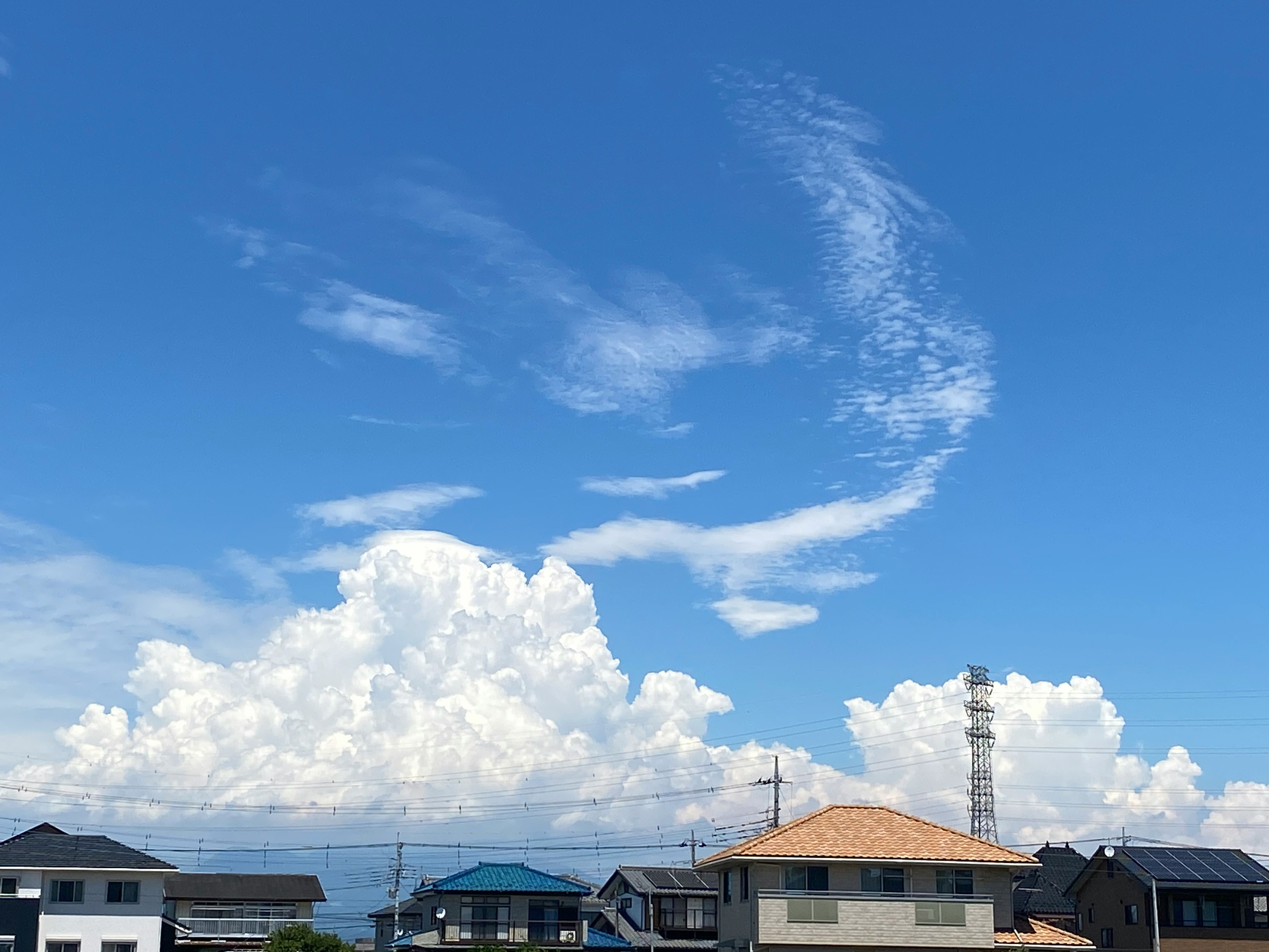 青空と白い雲が広がる風景と住宅のシルエット