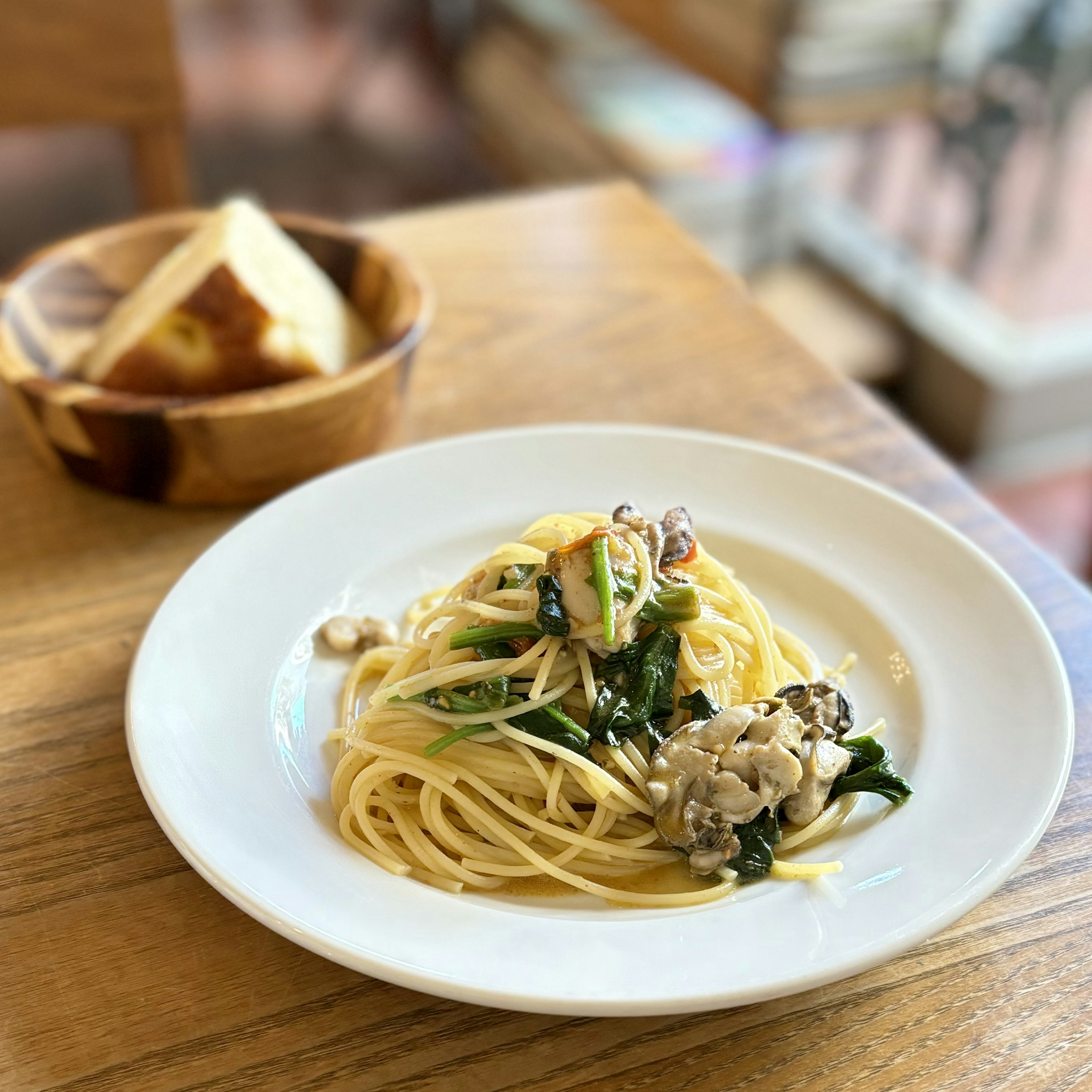 Assiette de spaghetti avec sauce crémeuse et légumes à côté d'un bol de pain