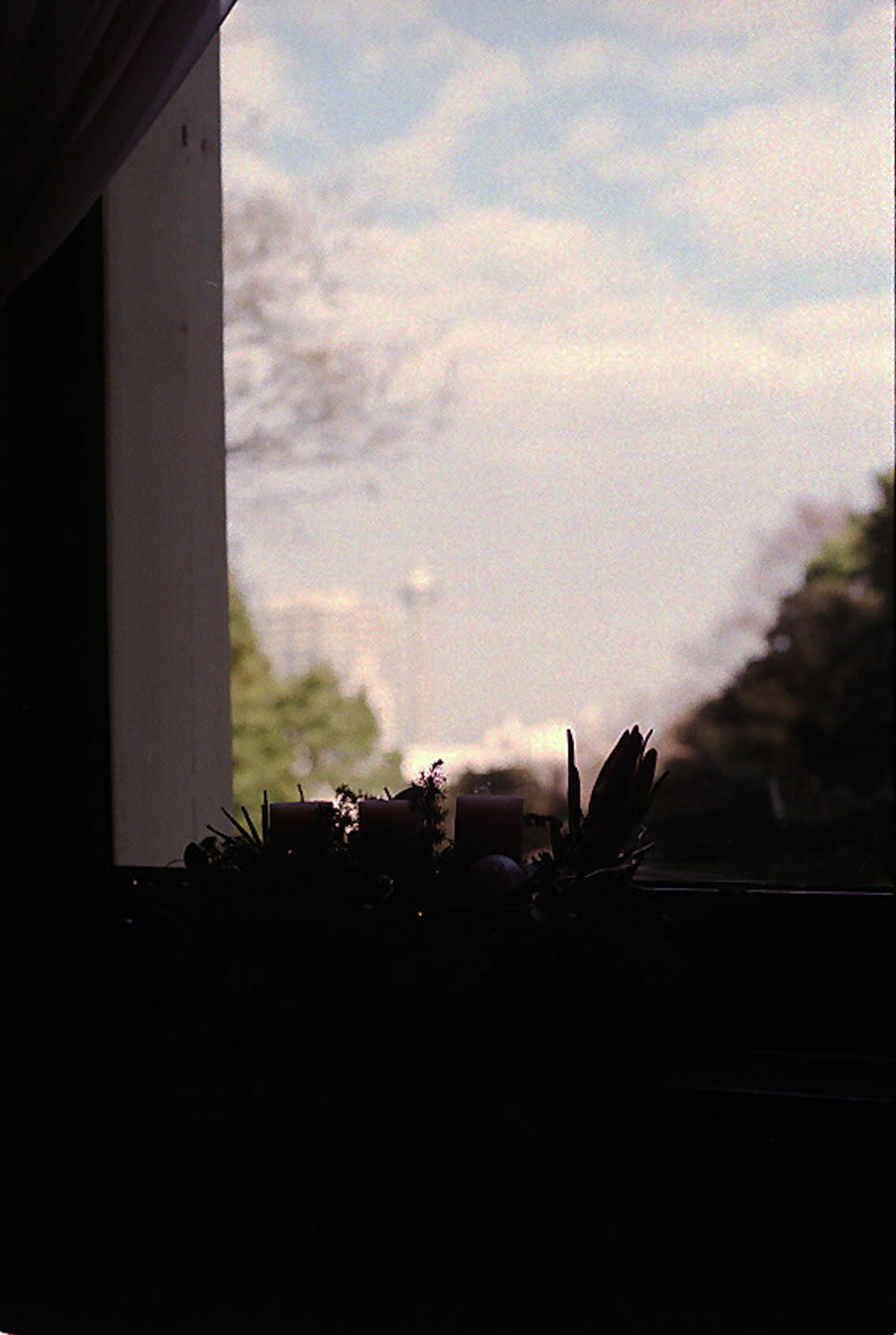 View of a cloudy sky and green landscape from a window