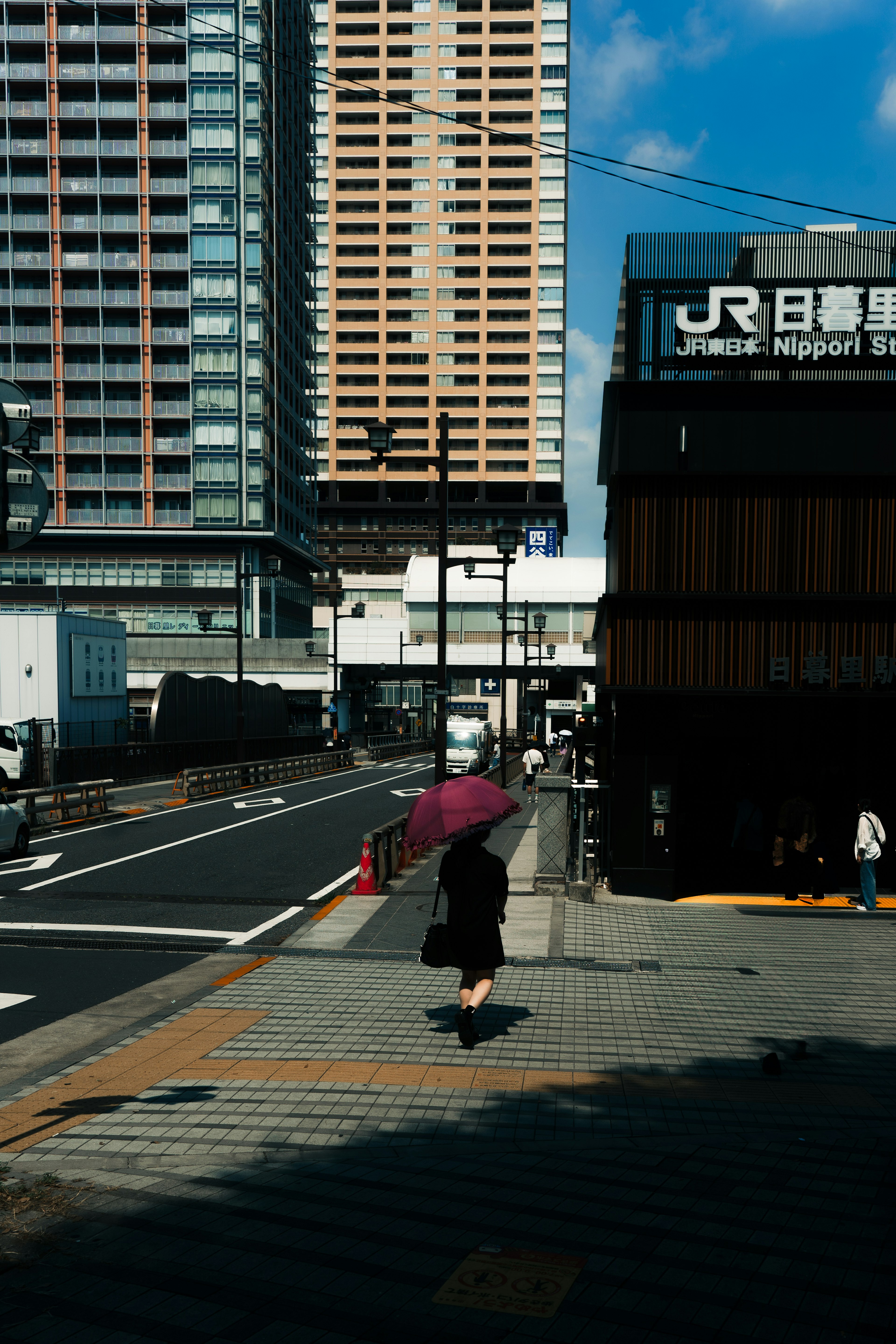 Une femme marchant avec un parapluie dans un paysage urbain avec des immeubles et une gare