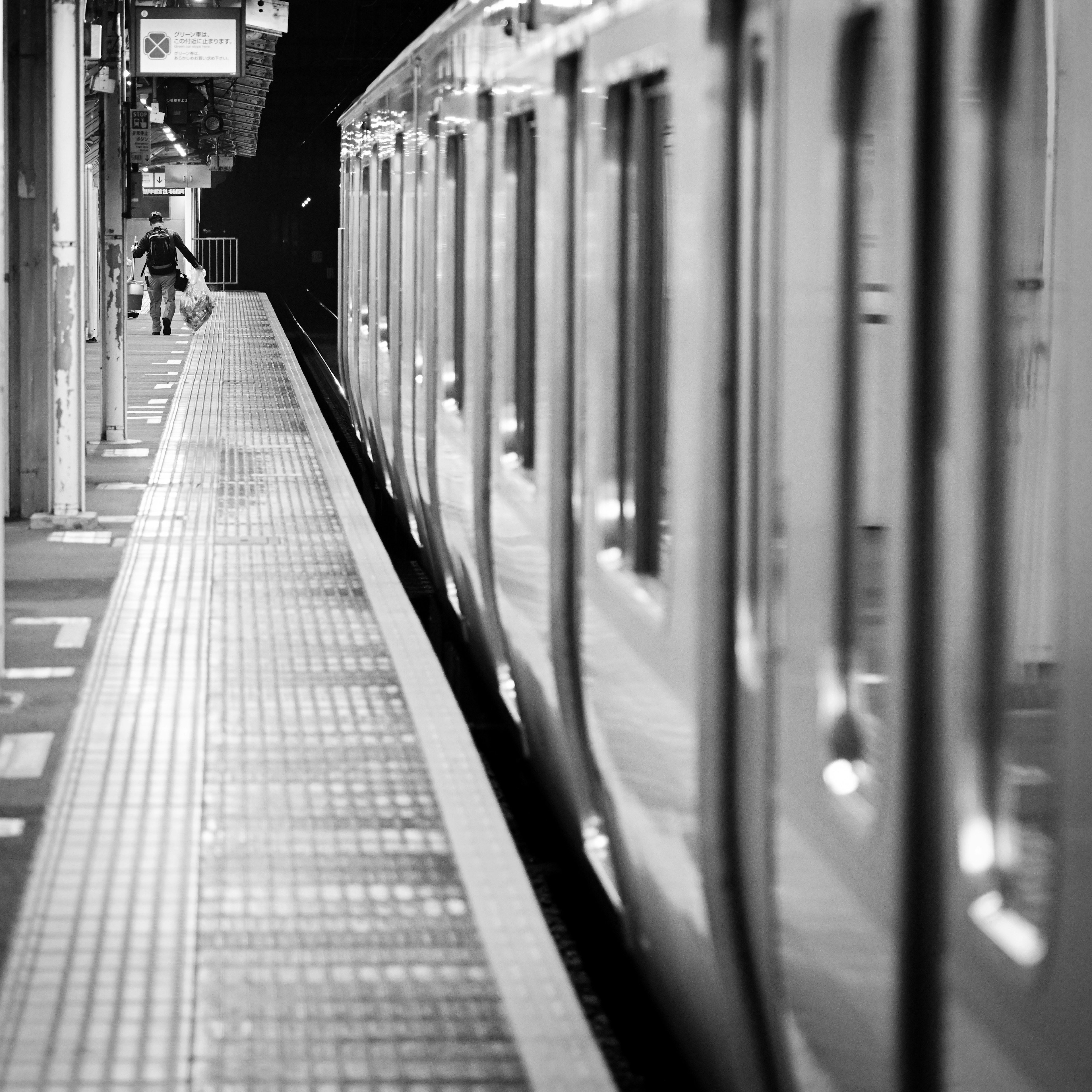 Eine Person wartet an einem Bahnsteig bei Nacht