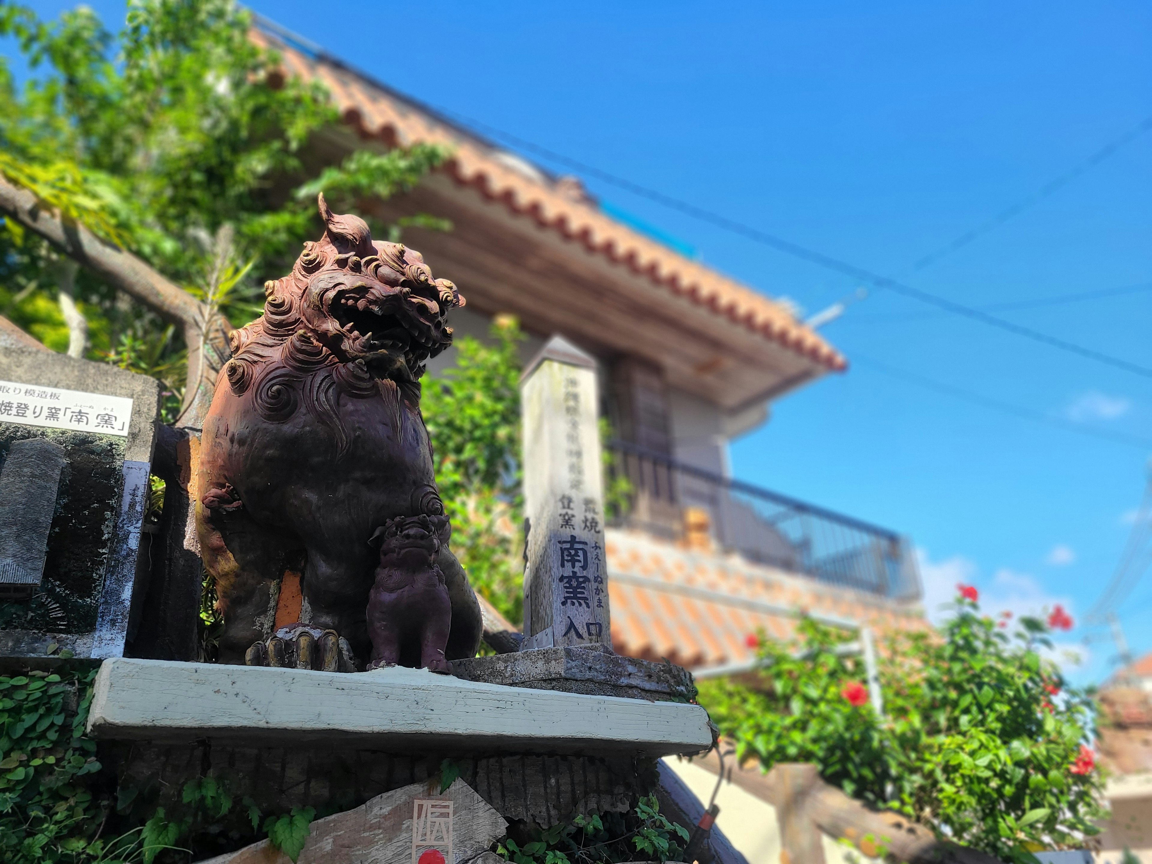 Patung Shisa di depan rumah dengan langit biru