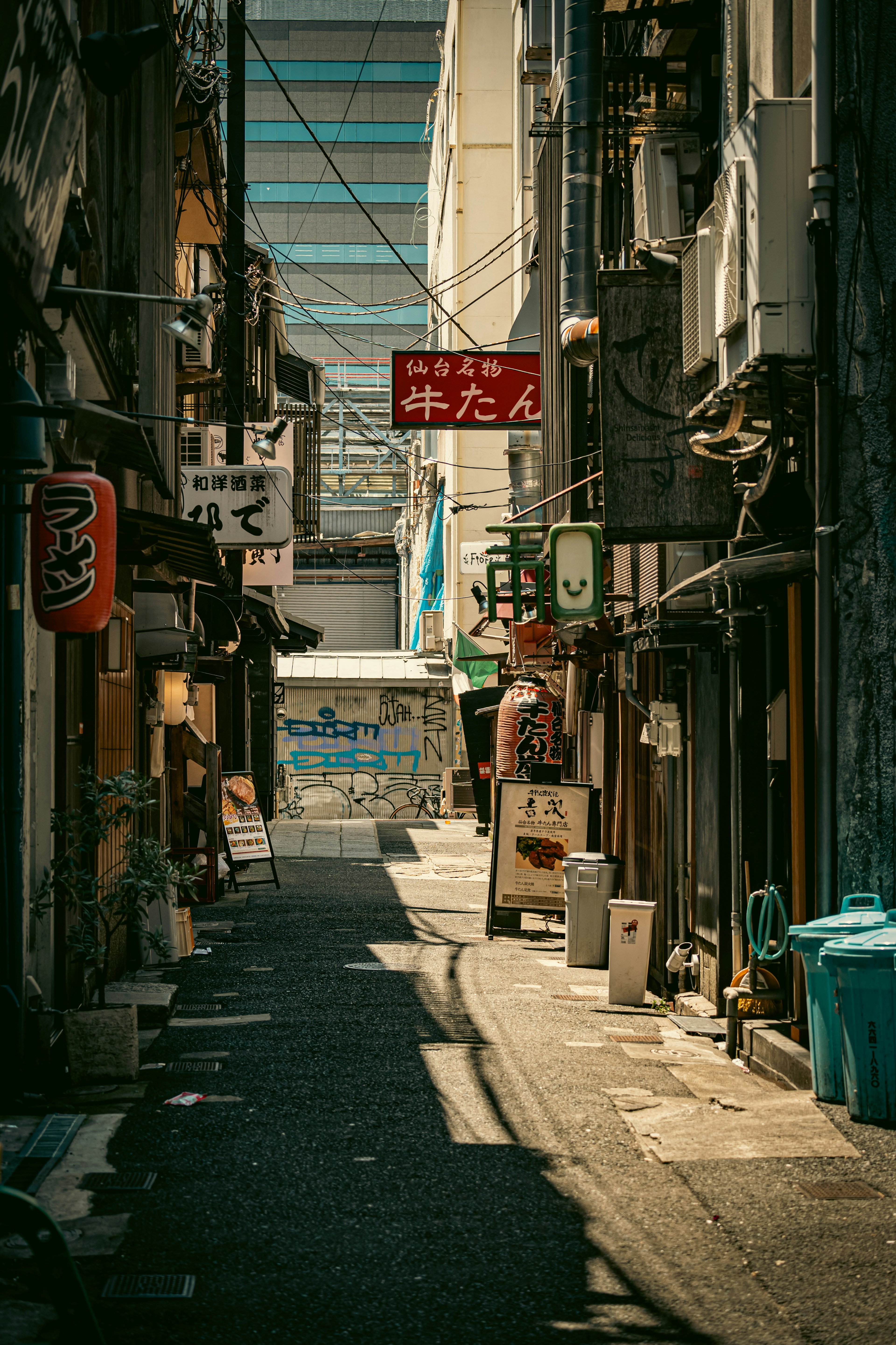 狹窄巷道配有餐廳招牌和藍色垃圾桶