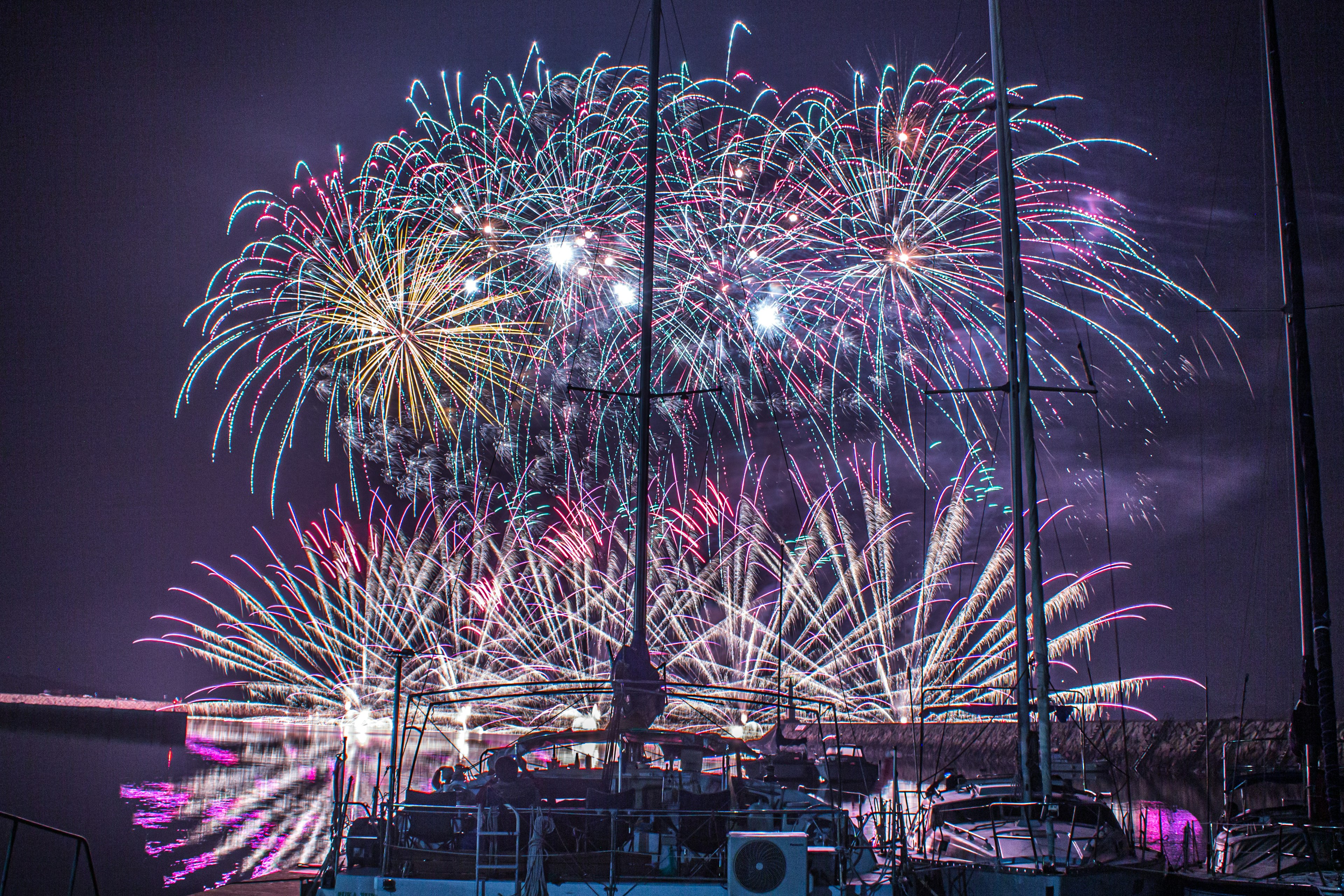 Spettacolo di fuochi d'artificio colorati che illuminano il cielo notturno con un veliero in primo piano