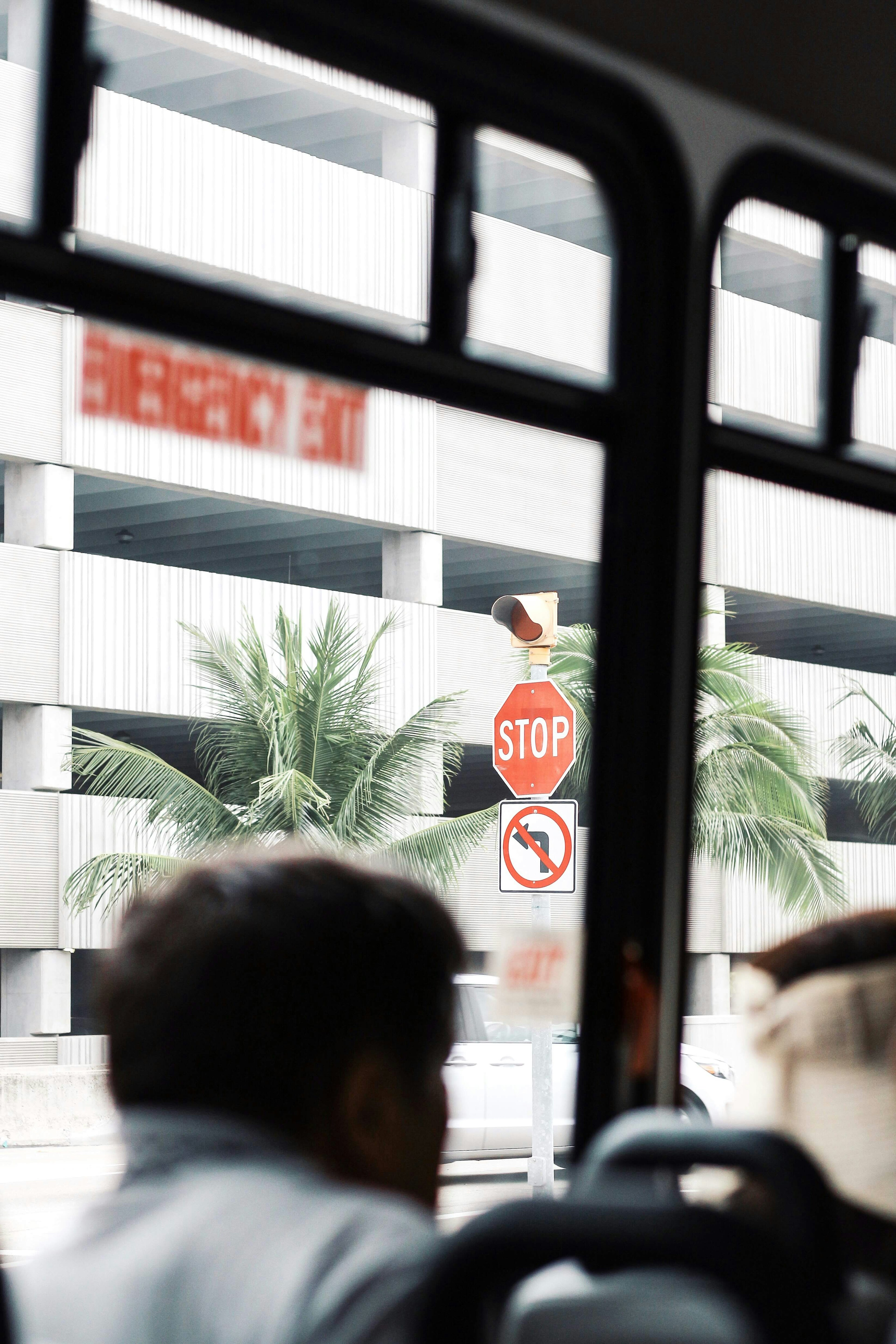 View through a bus window showing a stop sign and palm trees