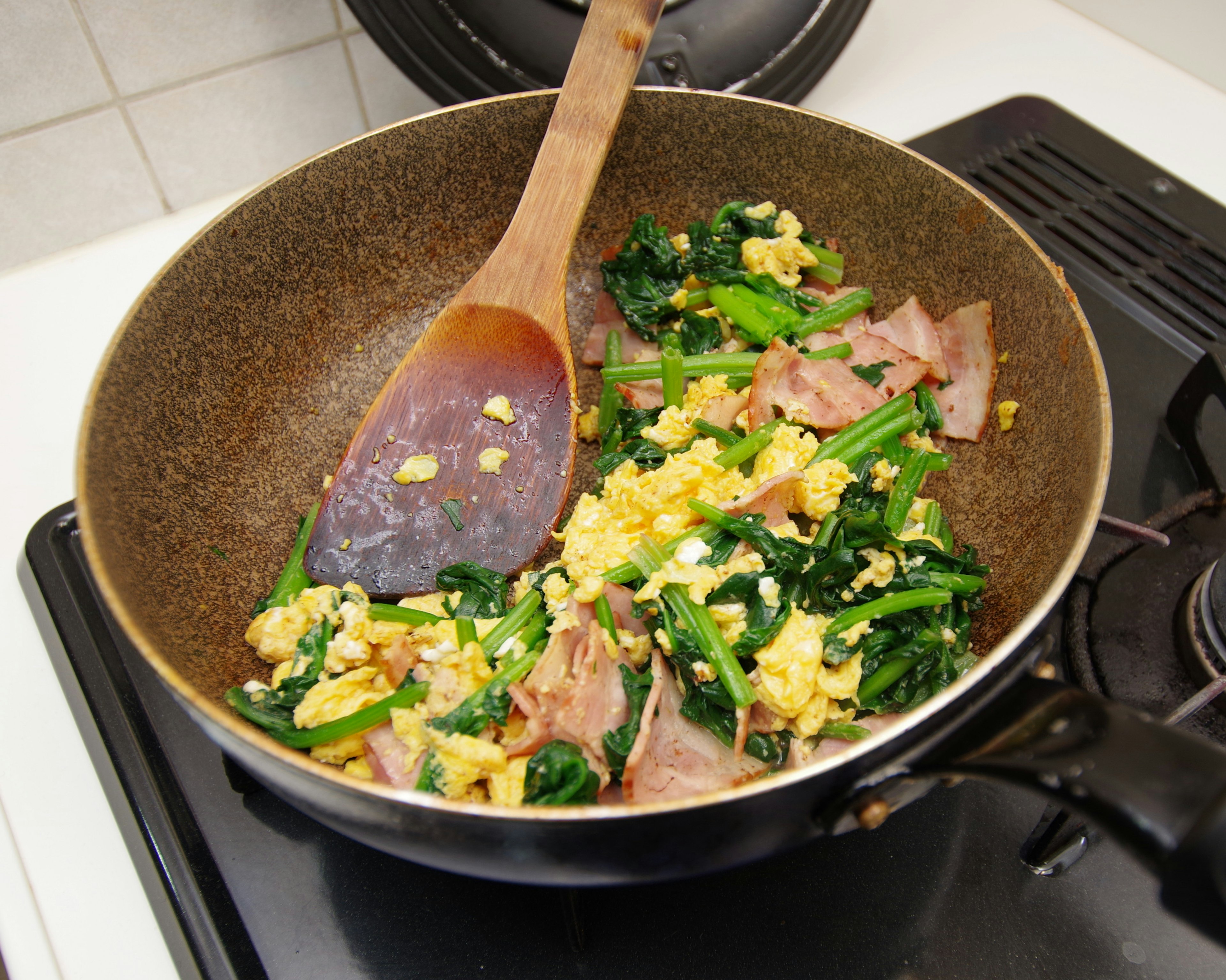 Huevos revueltos con verduras y jamón en una sartén