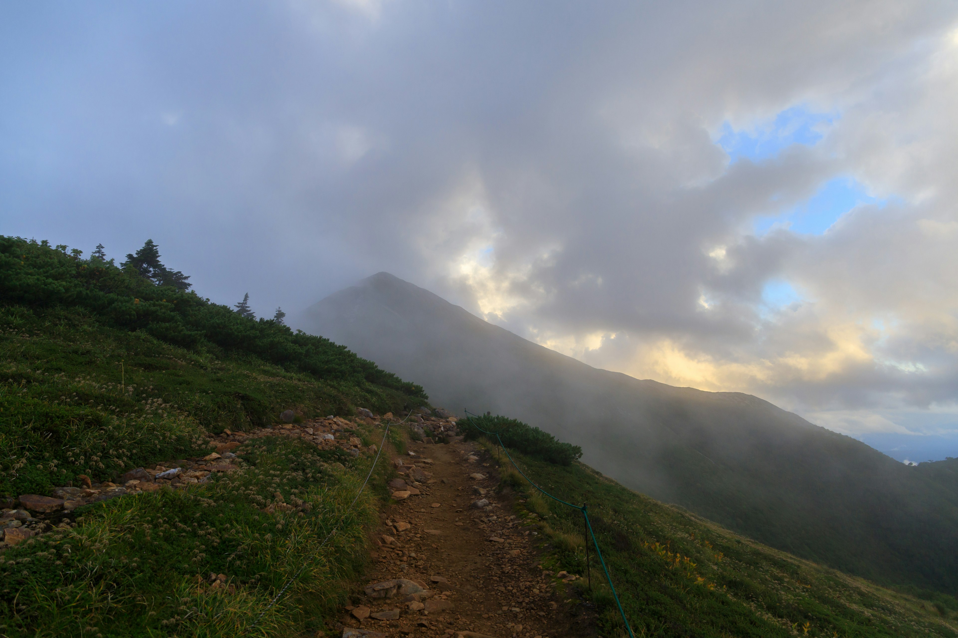 Sendero montañoso brumoso con toques de cielo azul