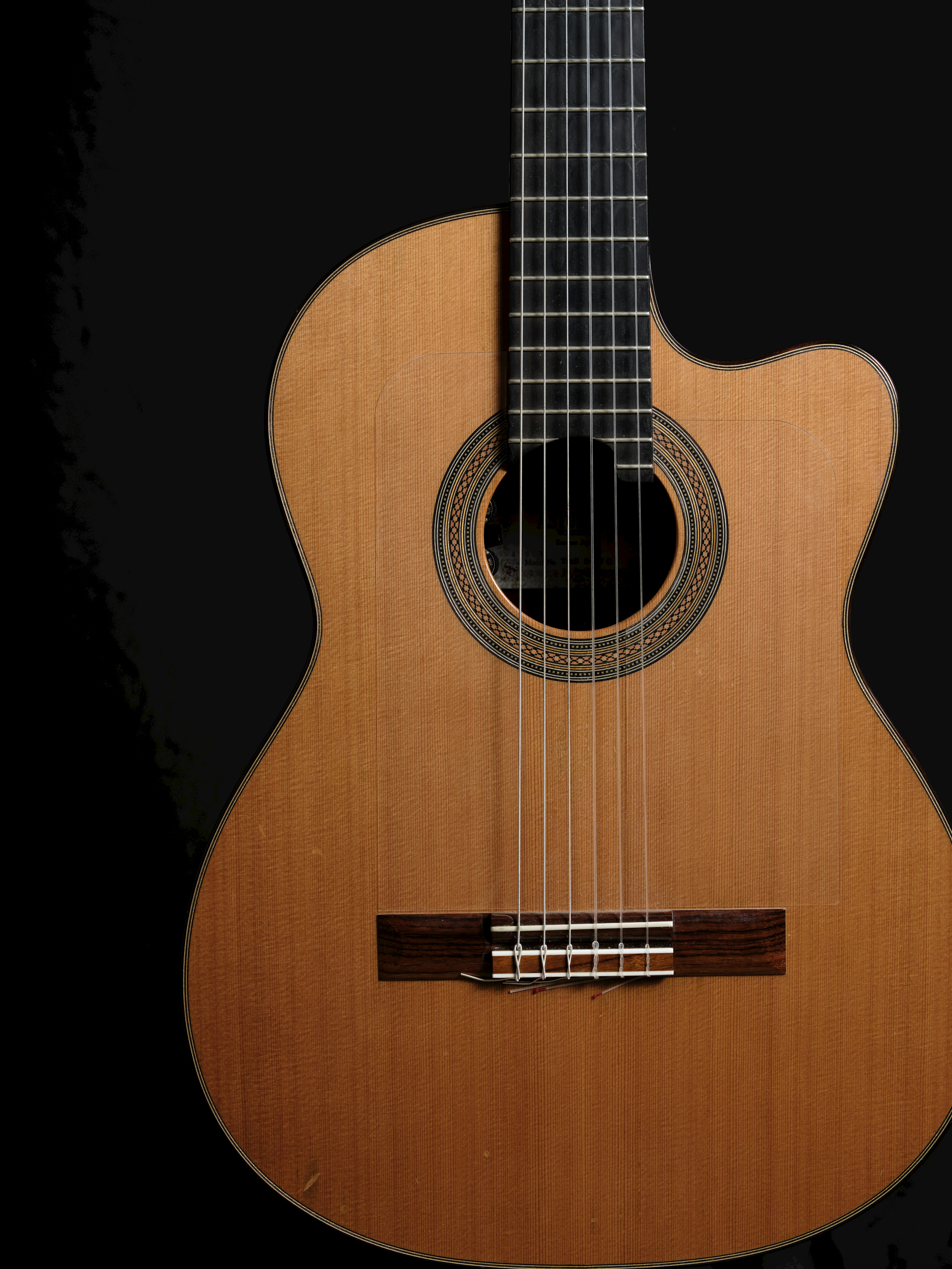 Close-up of a wooden acoustic guitar beautiful design against a black background