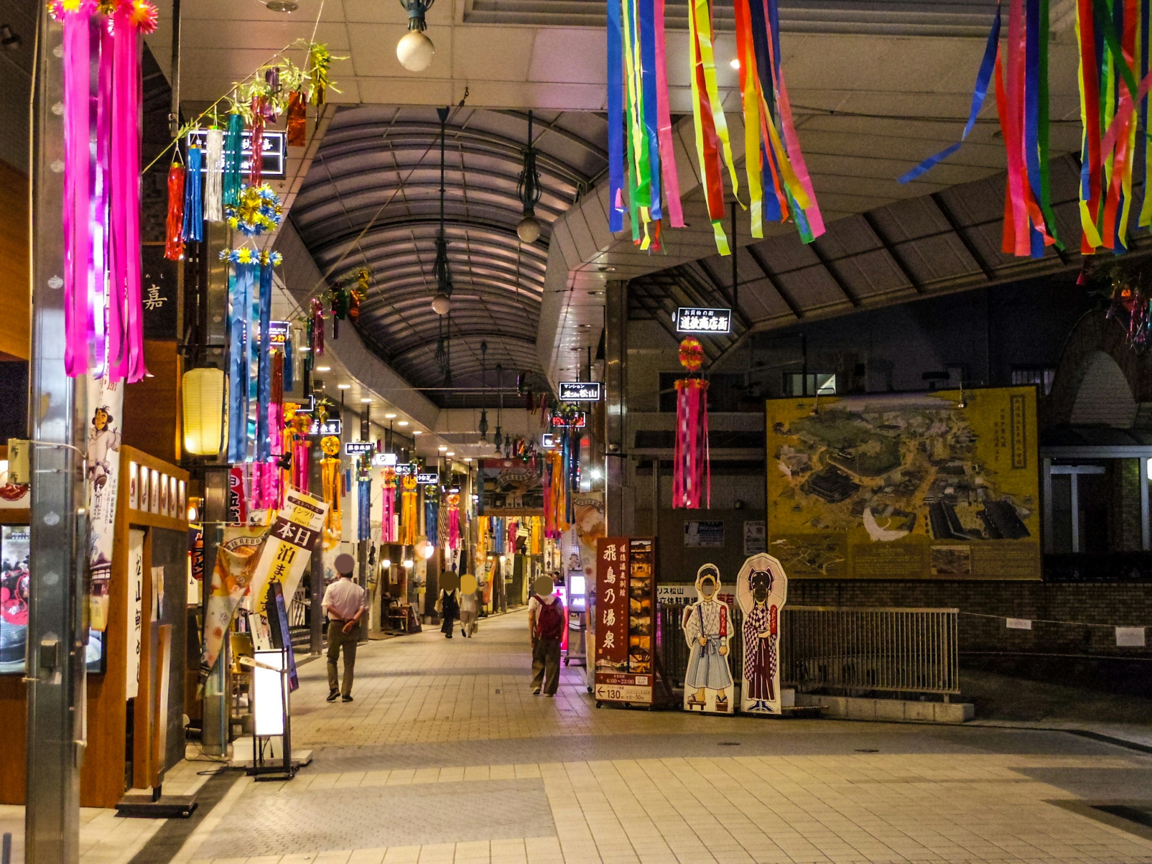 Vibrant shopping street with colorful decorations hanging overhead people walking