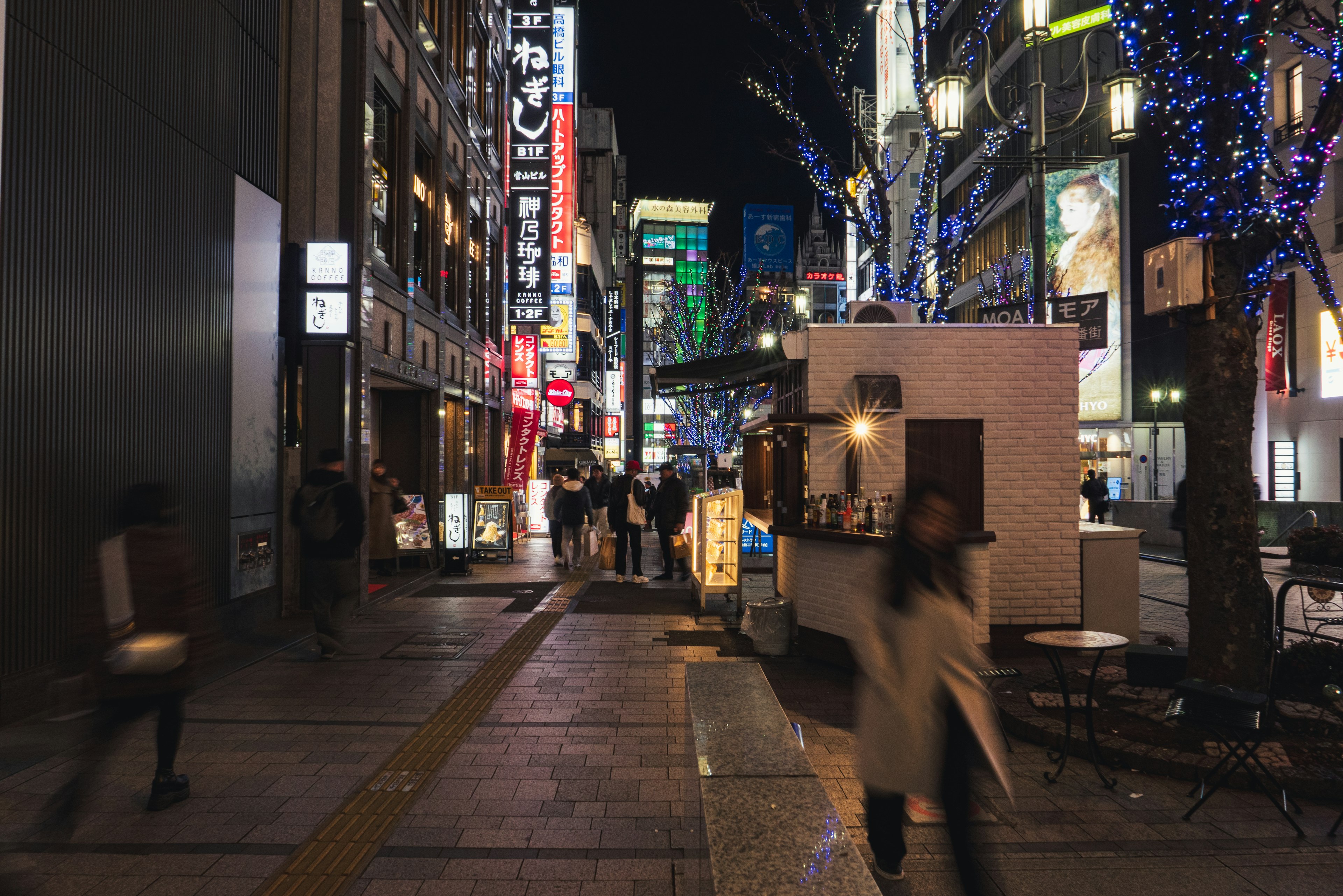 Bustling street scene at night with neon signs and pedestrians