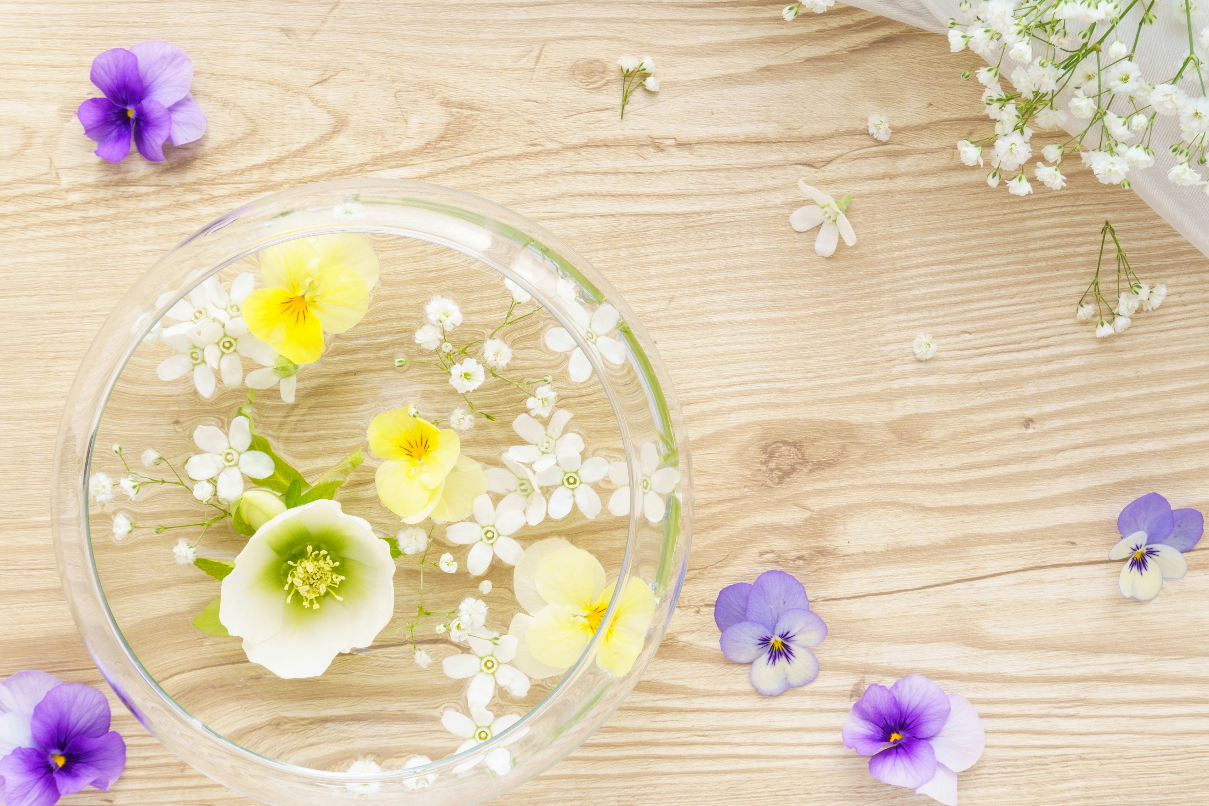 Un bellissimo arrangiamento di fiori gialli e fiori bianchi che galleggiano in una ciotola trasparente