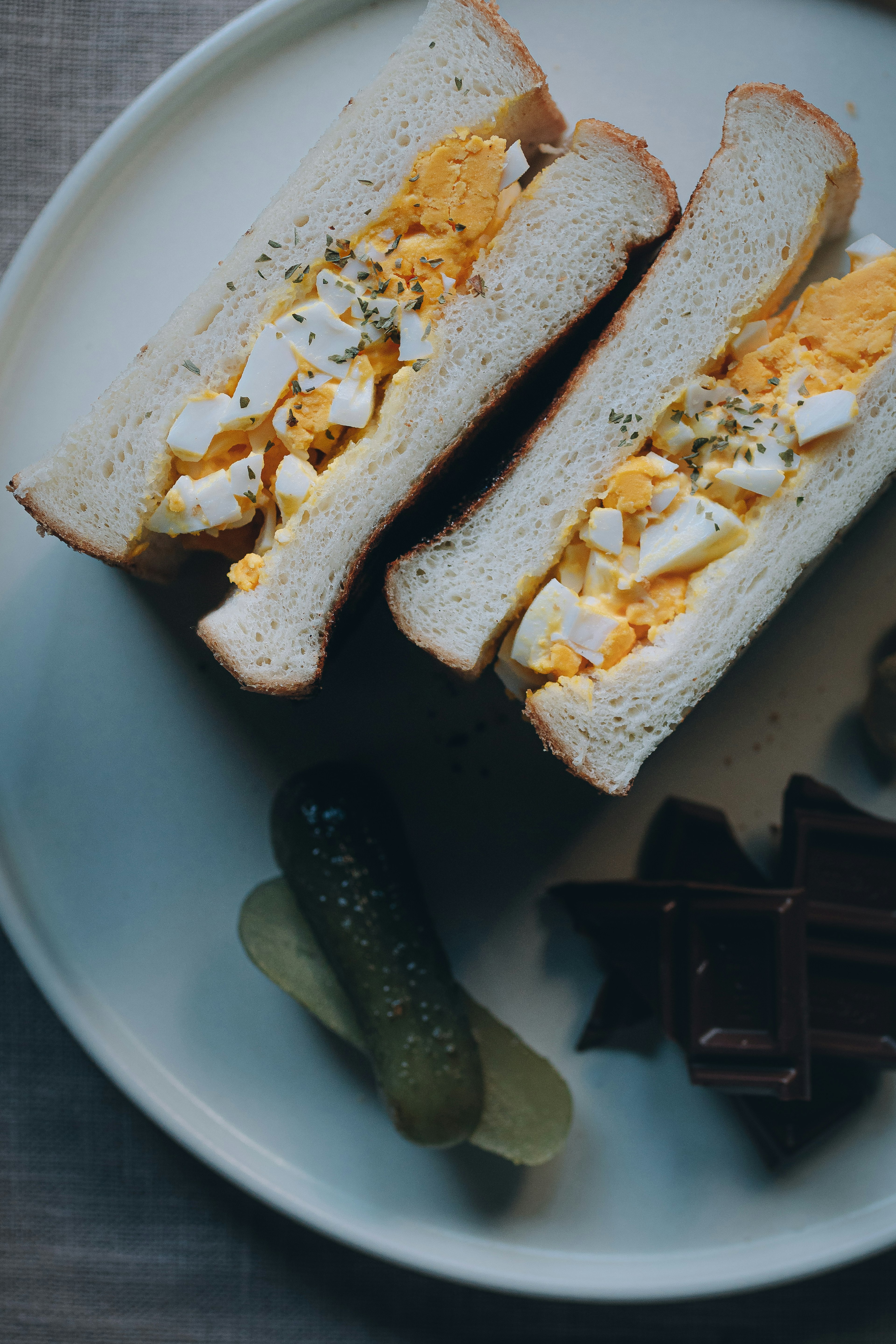 Sándwich de huevo con pepinillos en un plato blanco