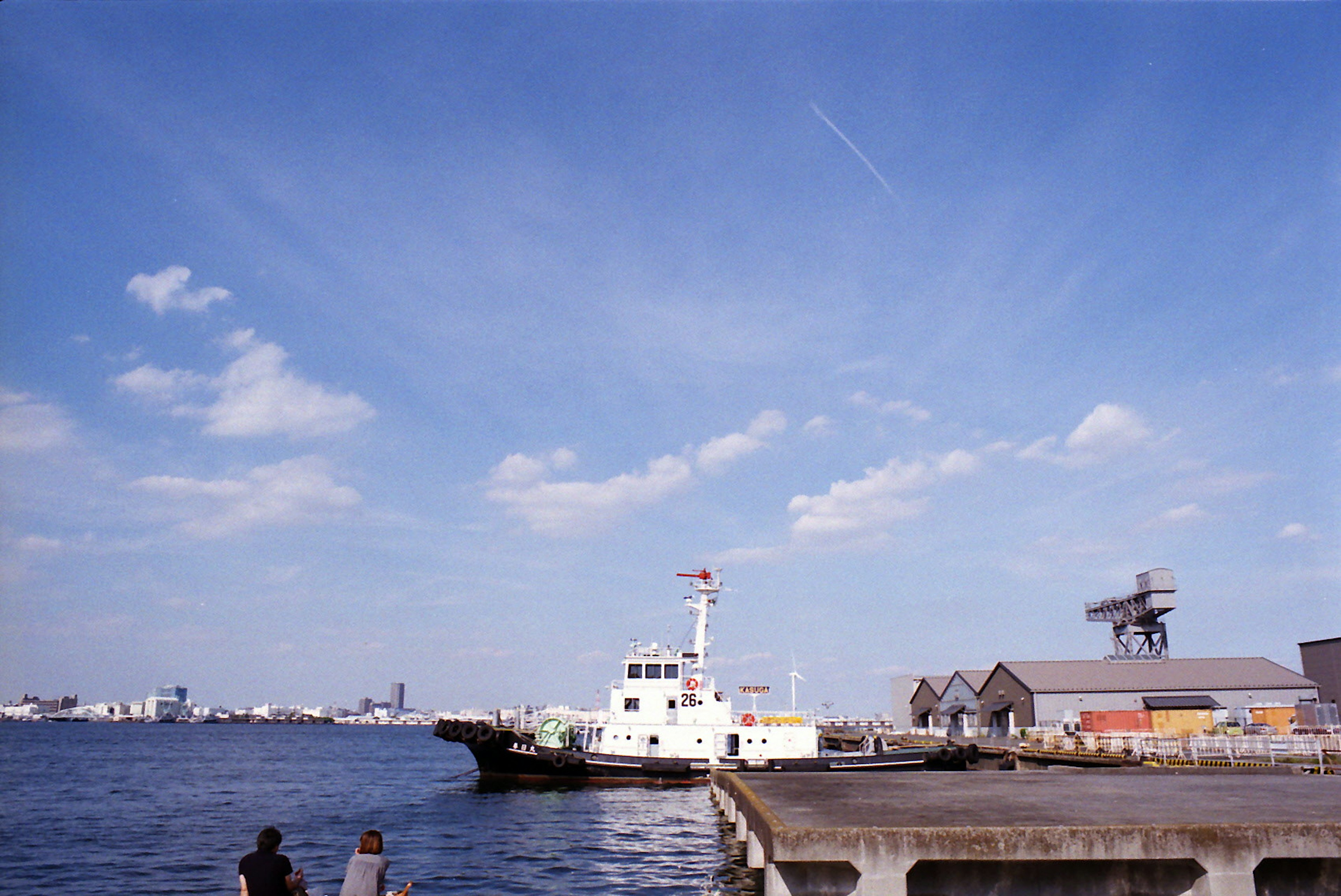 A white boat docked by the pier under a blue sky with clouds