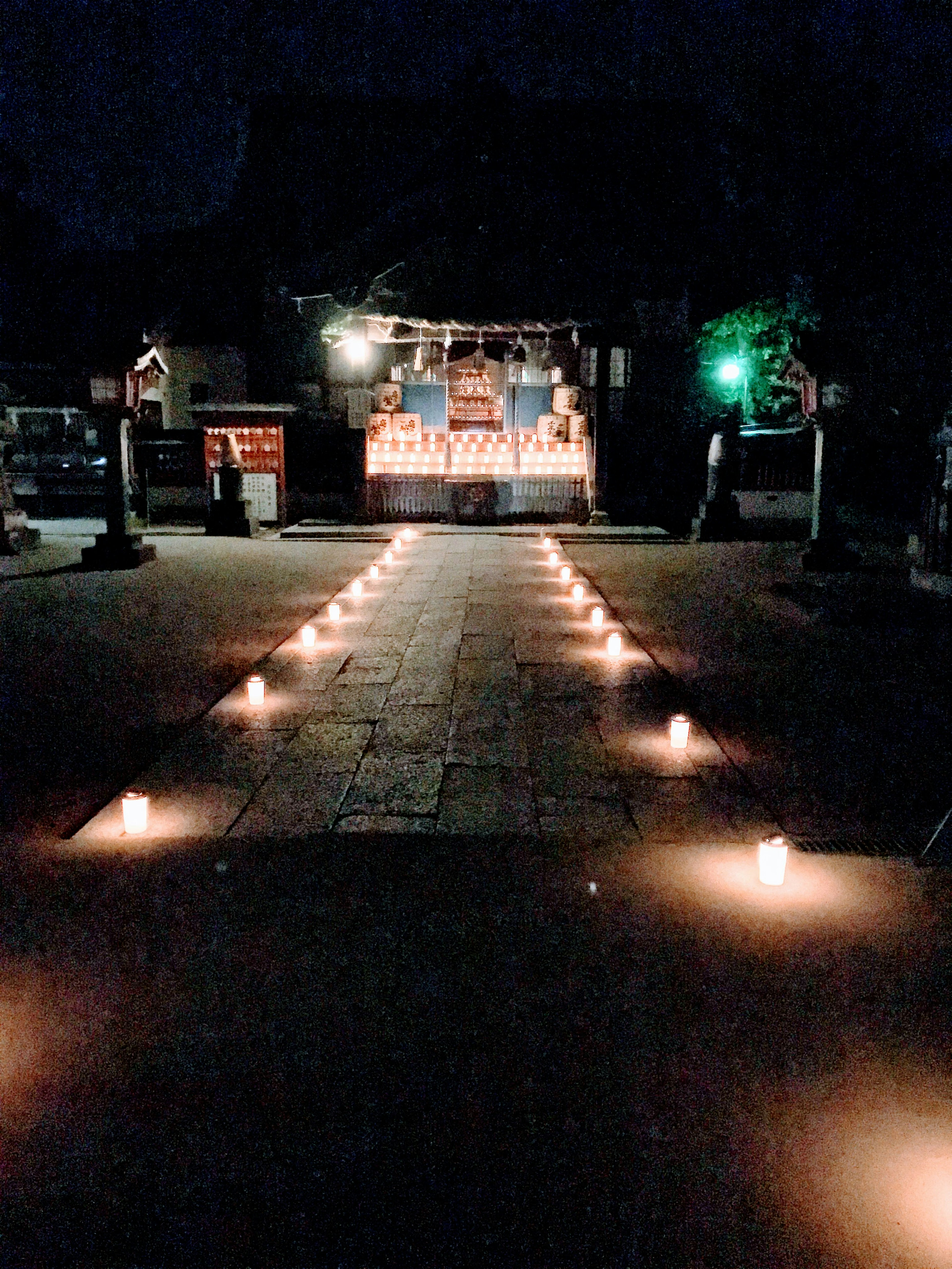 A pathway lined with candles leading to a shrine at night